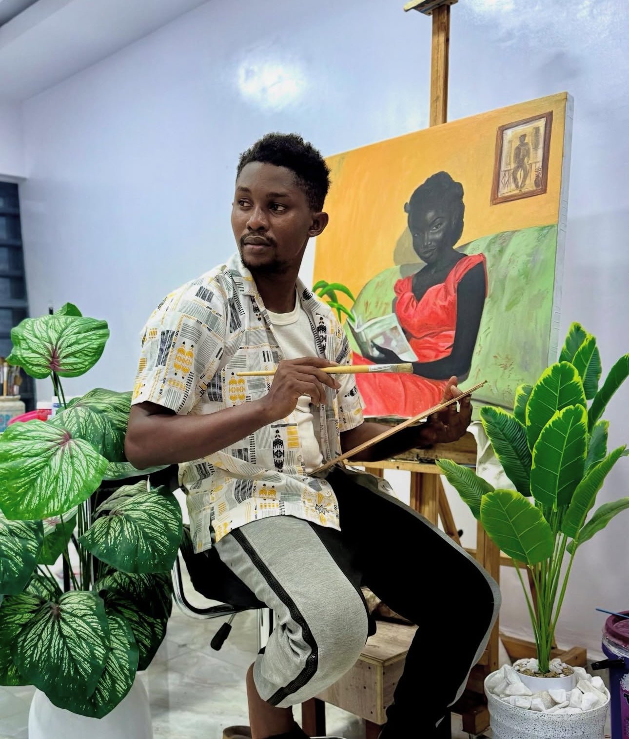 A man sits on a stool painting a portrait of a woman in a red dress. He holds a brush and palette, surrounded by green potted plants, with the easel and canvas behind him.