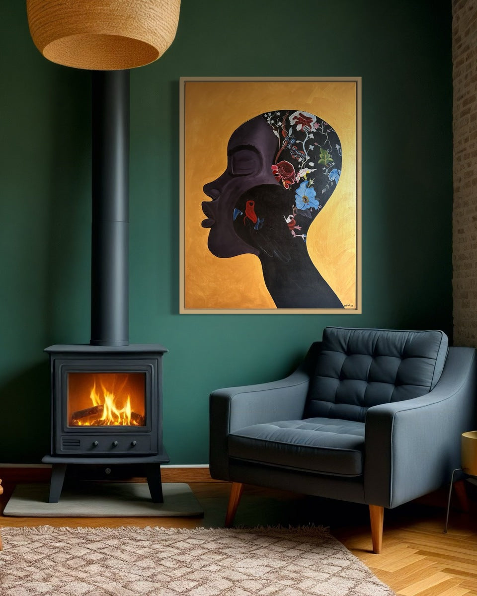 A cozy room with a dark green wall, wood-burning stove, modern dark blue armchair, and "Manifesting"—a vibrant hand-signed acrylic on canvas painting by Azizo featuring a floral and bird silhouette—hanging above the stove.