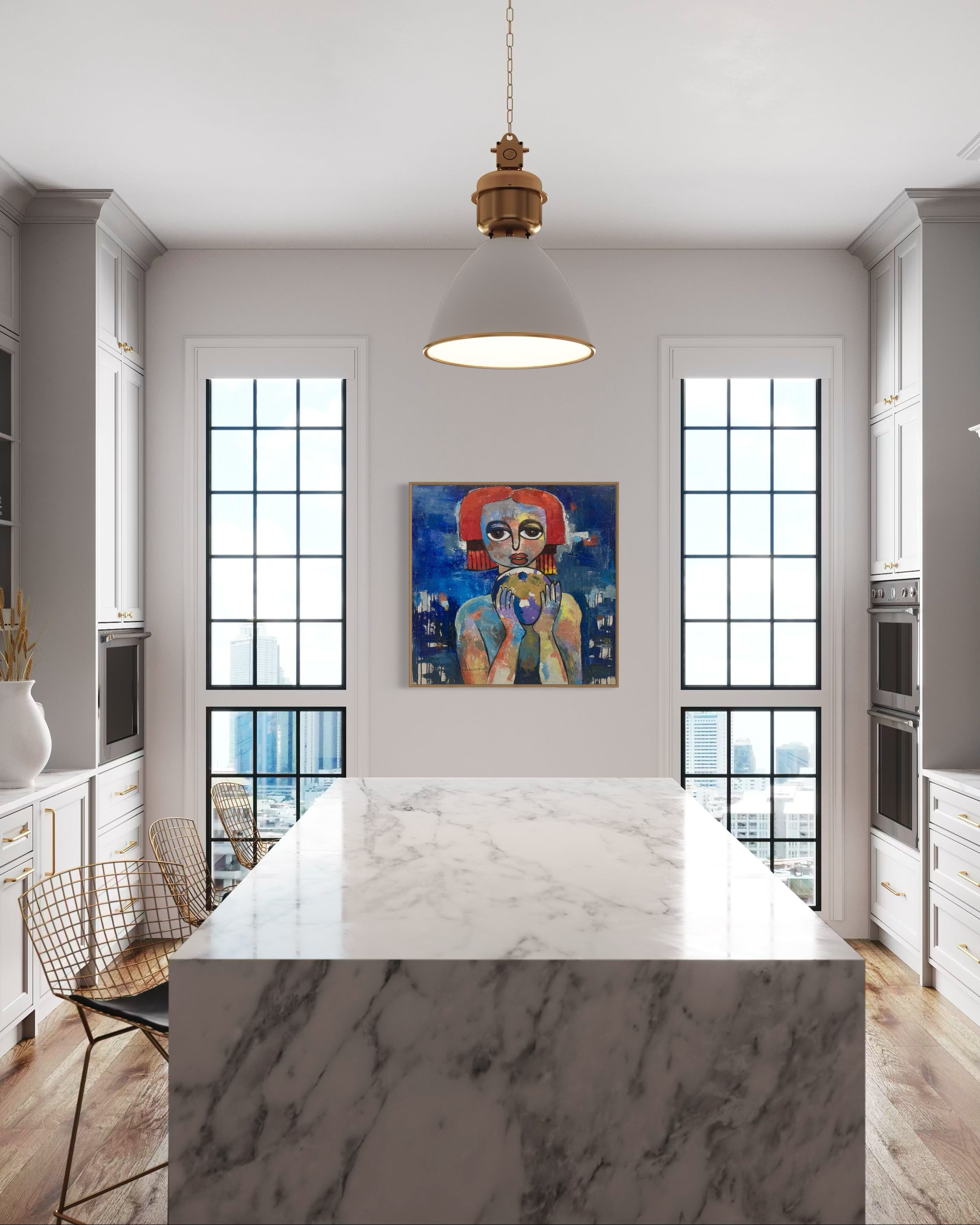 A modern kitchen with a large marble island, gold wire chairs, tall windows, and Achike Anayo's hand-signed artwork 'My World, Destiny Is In My Hands' displayed between the windows. A pendant light hangs above the island.