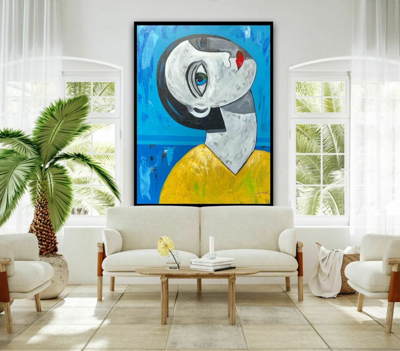 A modern living room with white sofas, a wooden coffee table, a potted palm, and "Gaze Of Hope" by Ifeanyi Admire—a large hand-signed acrylic on canvas abstract face painting in blue, yellow, white, and black tones—on the wall.