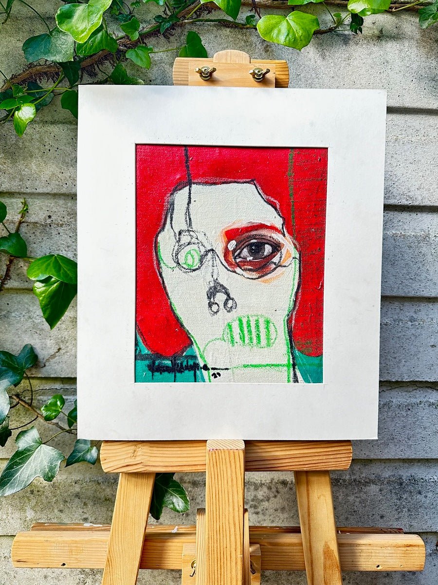 Act 4" by Olasunkanmi Oyelusi is a colorful abstract portrait on paper, hand-signed, showing an exaggerated face on a red background. The artwork is clipped to a wooden easel with green ivy and a gray stone wall in the background.