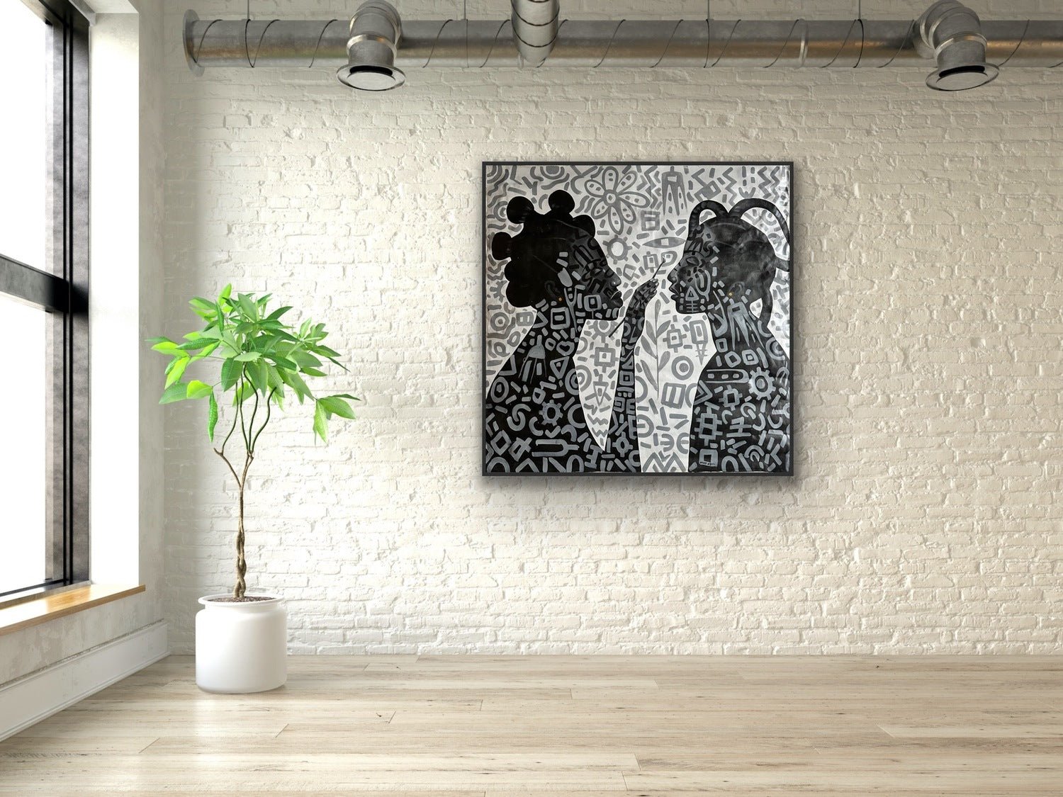 The Monochrome Large Acrylic Painting on Canvas, "Adornment" by Afuope Opeyemi, featuring two silhouetted figures, hangs on a white brick wall in a bright modern room with wood floors, a potted plant, and exposed ceiling pipes.