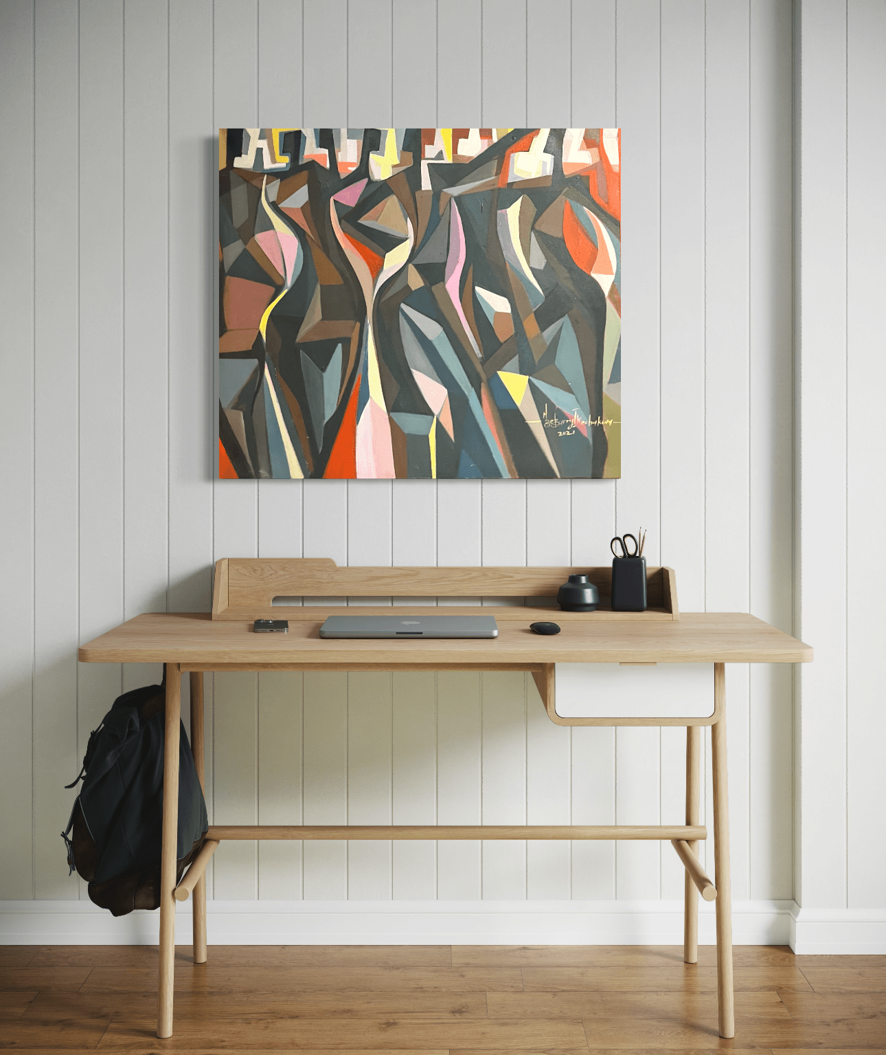 A minimalist wooden desk with a laptop, notebook, and office supplies sits against a white paneled wall, topped with 'The Red Man' 78x78 cm by Barry Ikechukwu; its abstract human forms add intrigue as a backpack hangs on the side.