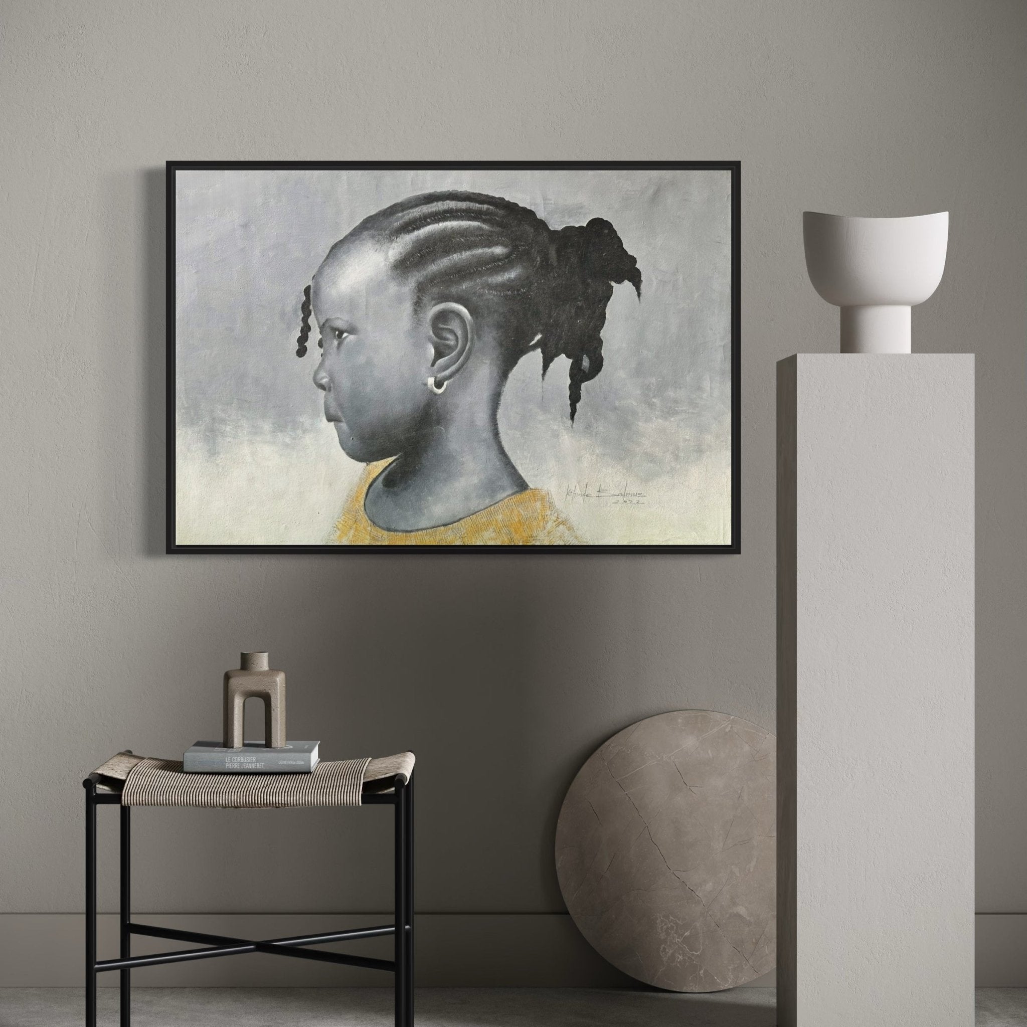 The Sweetest Thing" (98 x 60cm) by Kehinde Badmuss—a framed portrait of a young girl with braided cornrows—hangs on a gray wall above a black side table, while a pedestal nearby displays a white bowl and round stone.