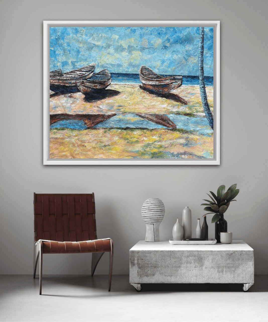 A modern living room with a brown leather chair, a low gray table with vases, and "Canoes by the Sea" Beach days 120 x 95cm by Sunday Oladele—a framed painting of boats on the beach beneath a blue sky.