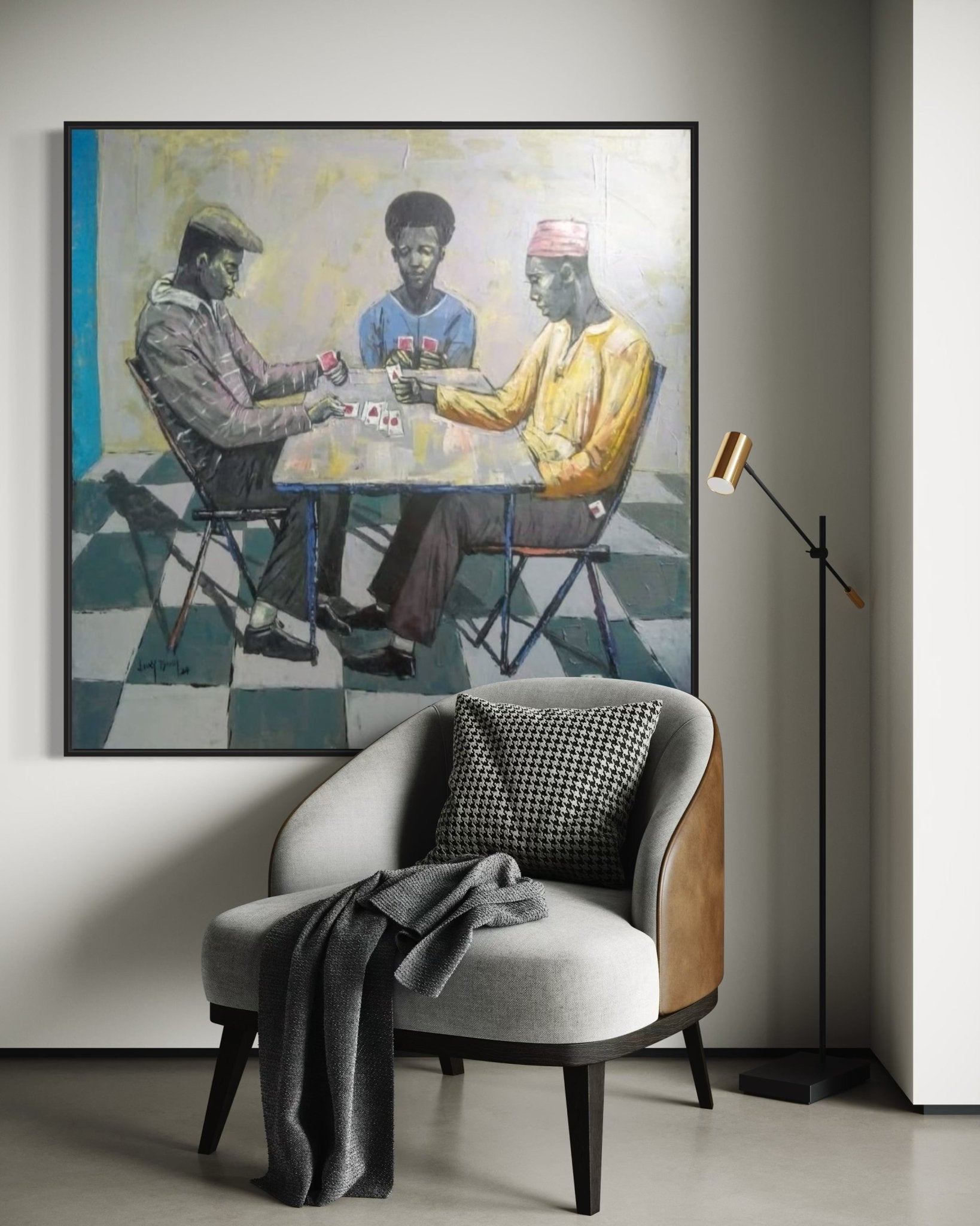 A modern armchair with a blanket sits before "Cartels" by Lucky Isaiah, a hand-signed painting of three people playing cards at a table, with a floor lamp placed next to the chair.