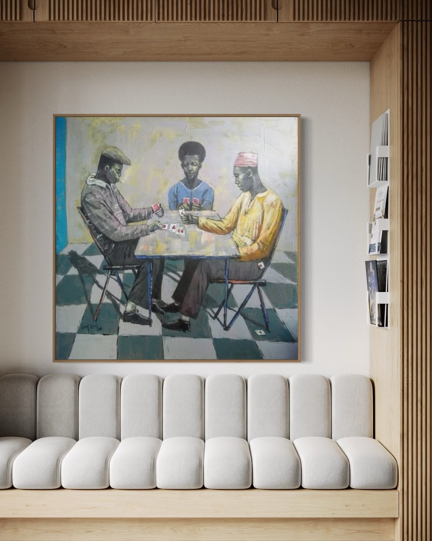 A modern living room with a light gray sofa and wooden accents, featuring "Cartels" by Lucky Isaiah—a large, hand-signed painting of three men playing cards at a table, complete with a certificate of authenticity above the sofa.