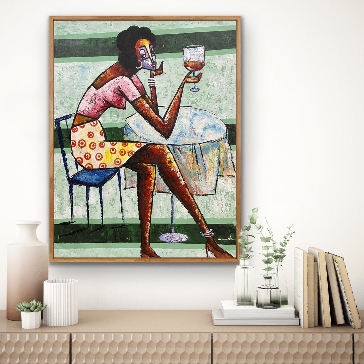 Cheers" by Ola Kuti is a vibrant acrylic on canvas of a woman with angular features in a yellow skirt with red circles, holding a wine glass. Hand-signed by the artist, this piece adds striking modern flair above any cabinet.