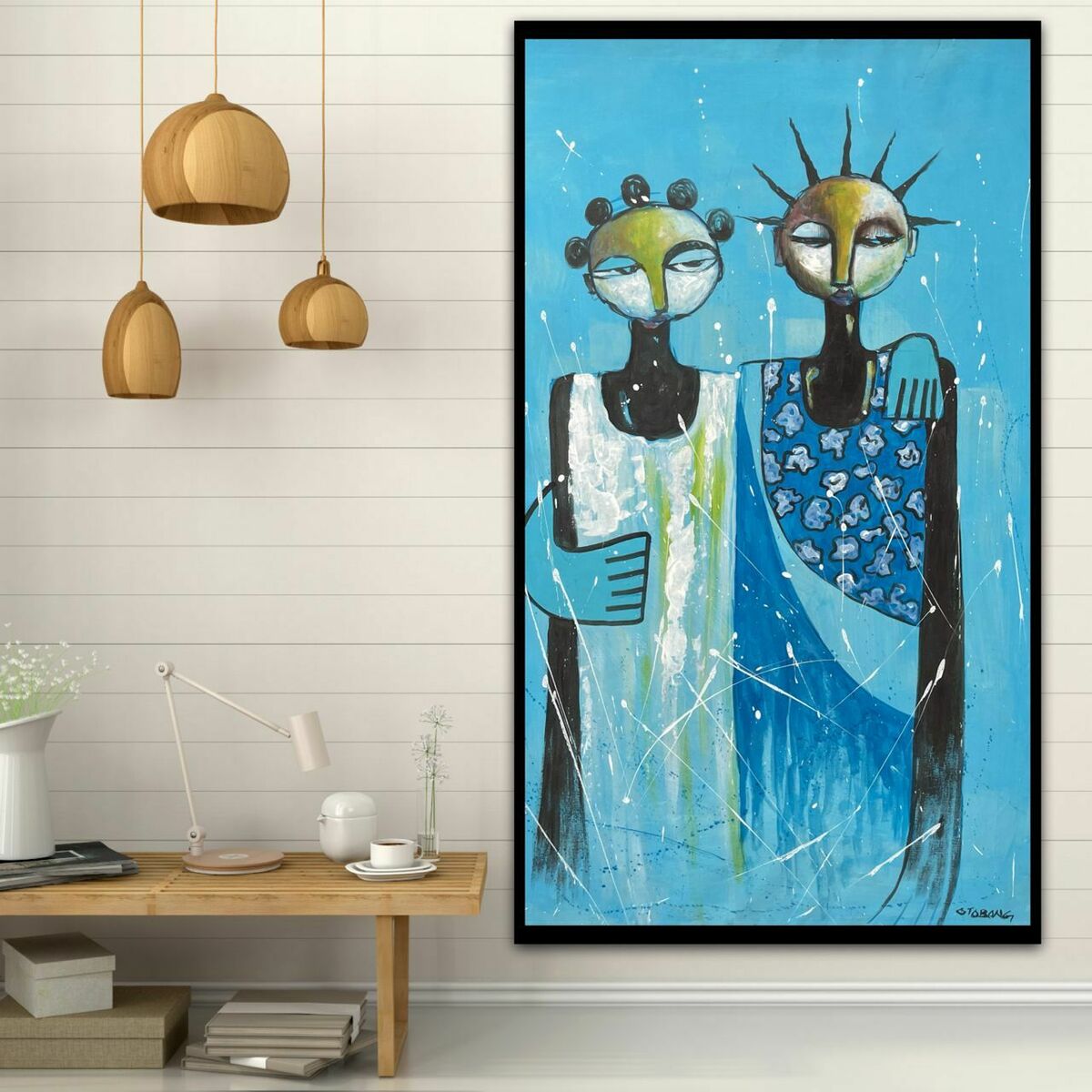 Painting features two colourful stylised figures with spiky hair, displayed in a modern room with wooden pendant lights, table