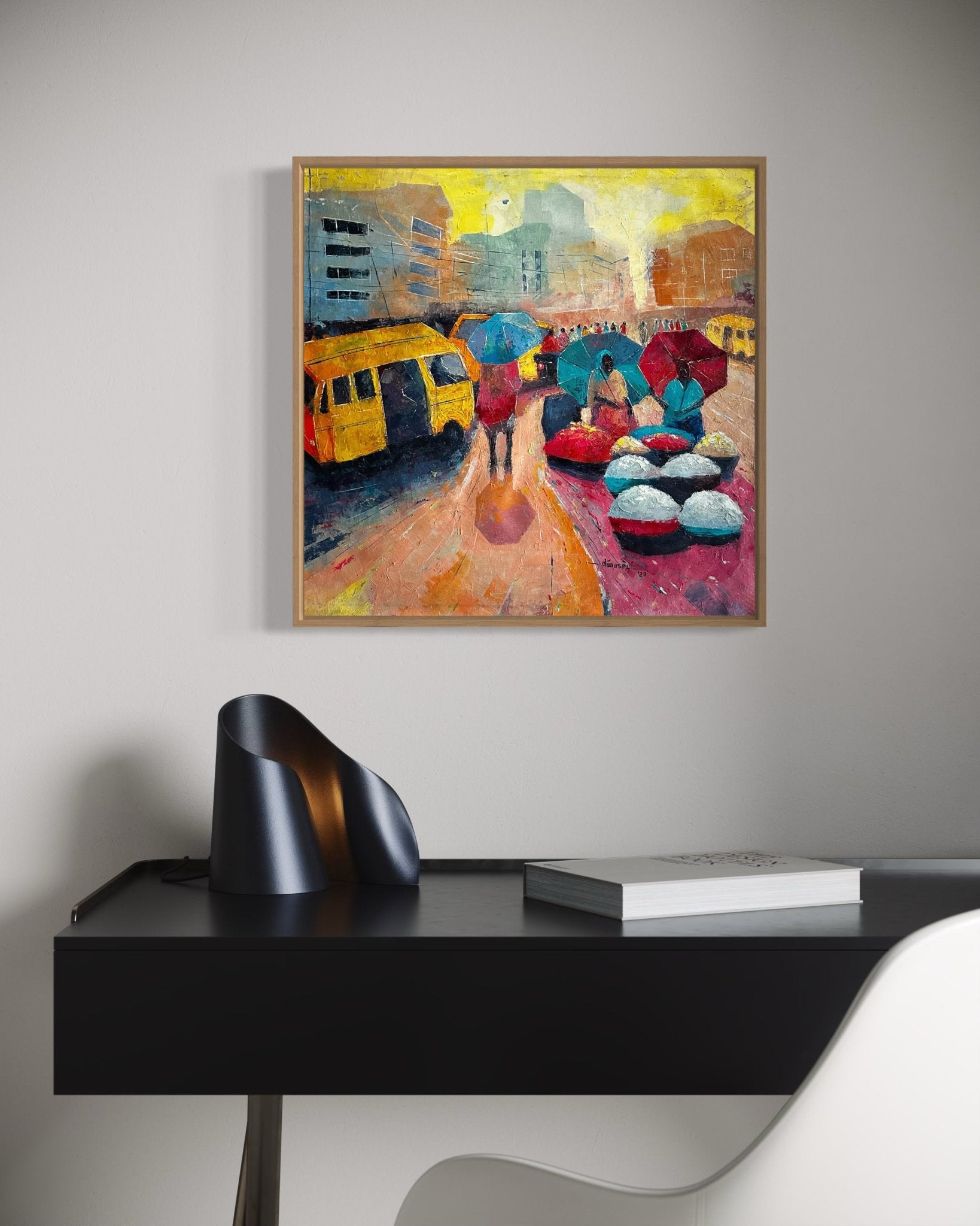 The "Danfo" painting by Bibianna African Art Collective, depicting Lagos street life with umbrellas, yellow buses, and baskets of goods, hangs on a plain wall above a modern black desk with a sculptural piece and open book.