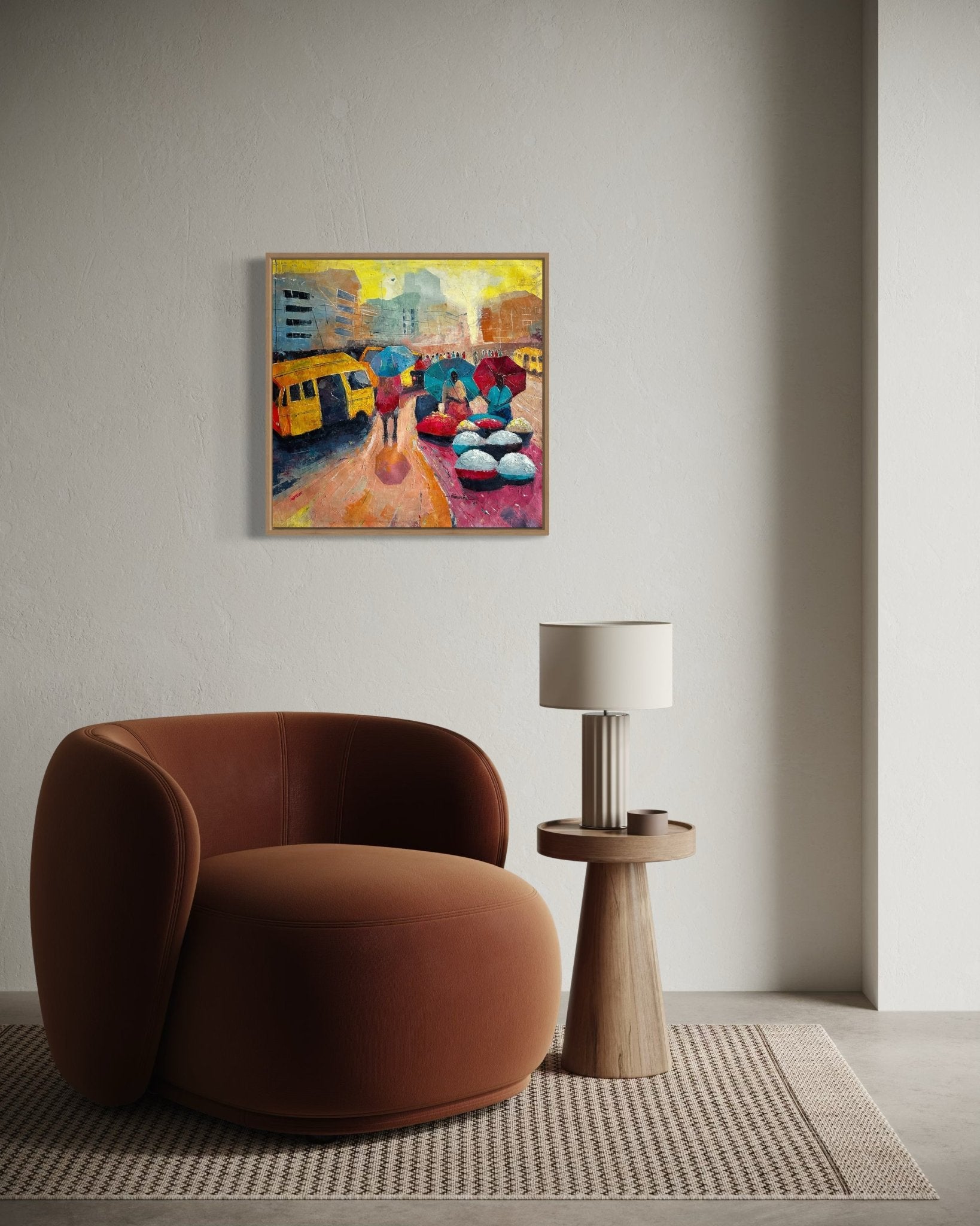 A modern living room with a round brown chair, a small side table with a white lamp, and "Danfo" by Bibianna African Art Collective—a colorful cityscape painting inspired by Lagos street life—hanging on the wall above.