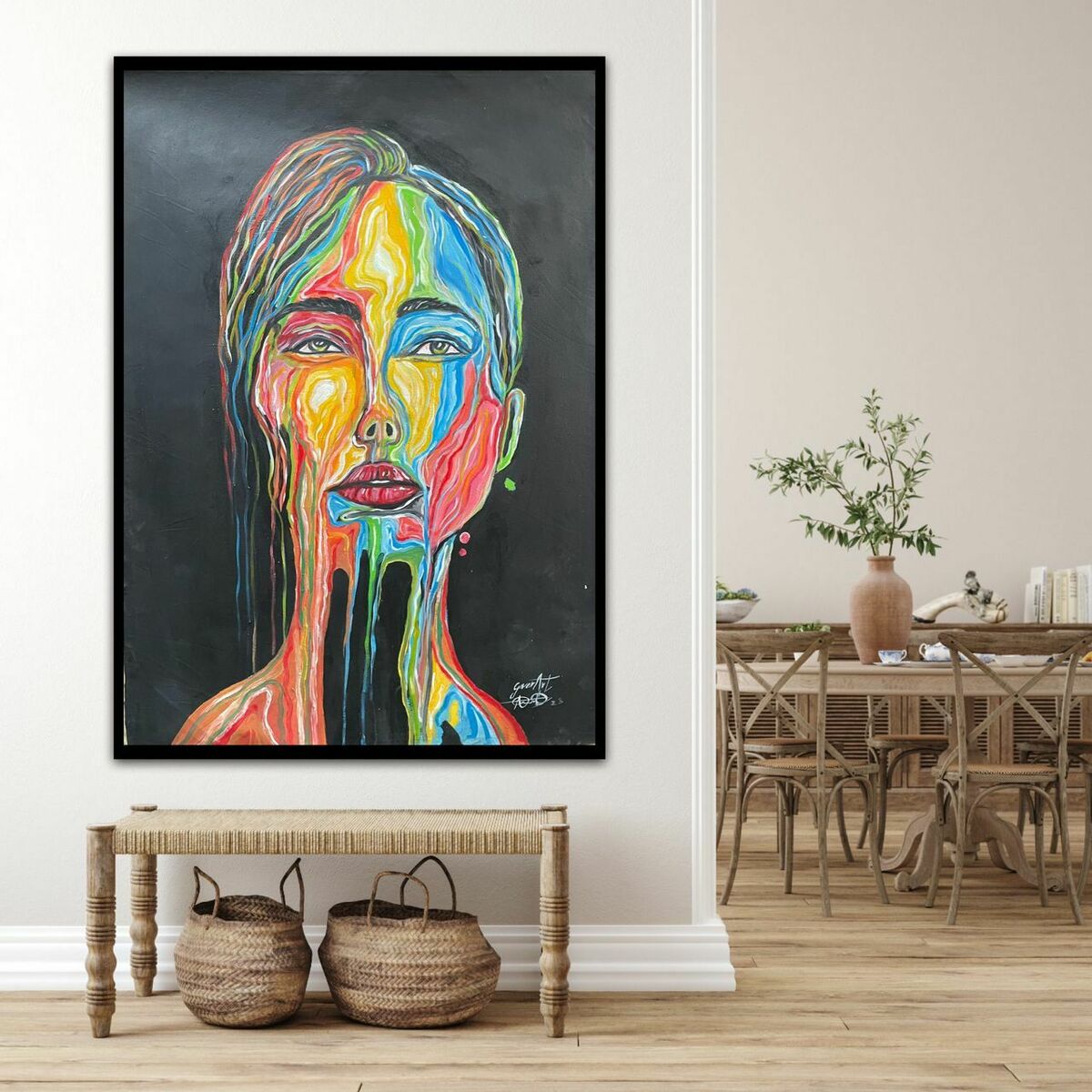 Emotive Colourful Portrait "Drops of Emotion" by Izuchukwu Giver, a hand-signed acrylic on canvas showing a woman's face with vibrant paint streaks, is displayed above a wooden bench with woven baskets; a dining table sits in the background.