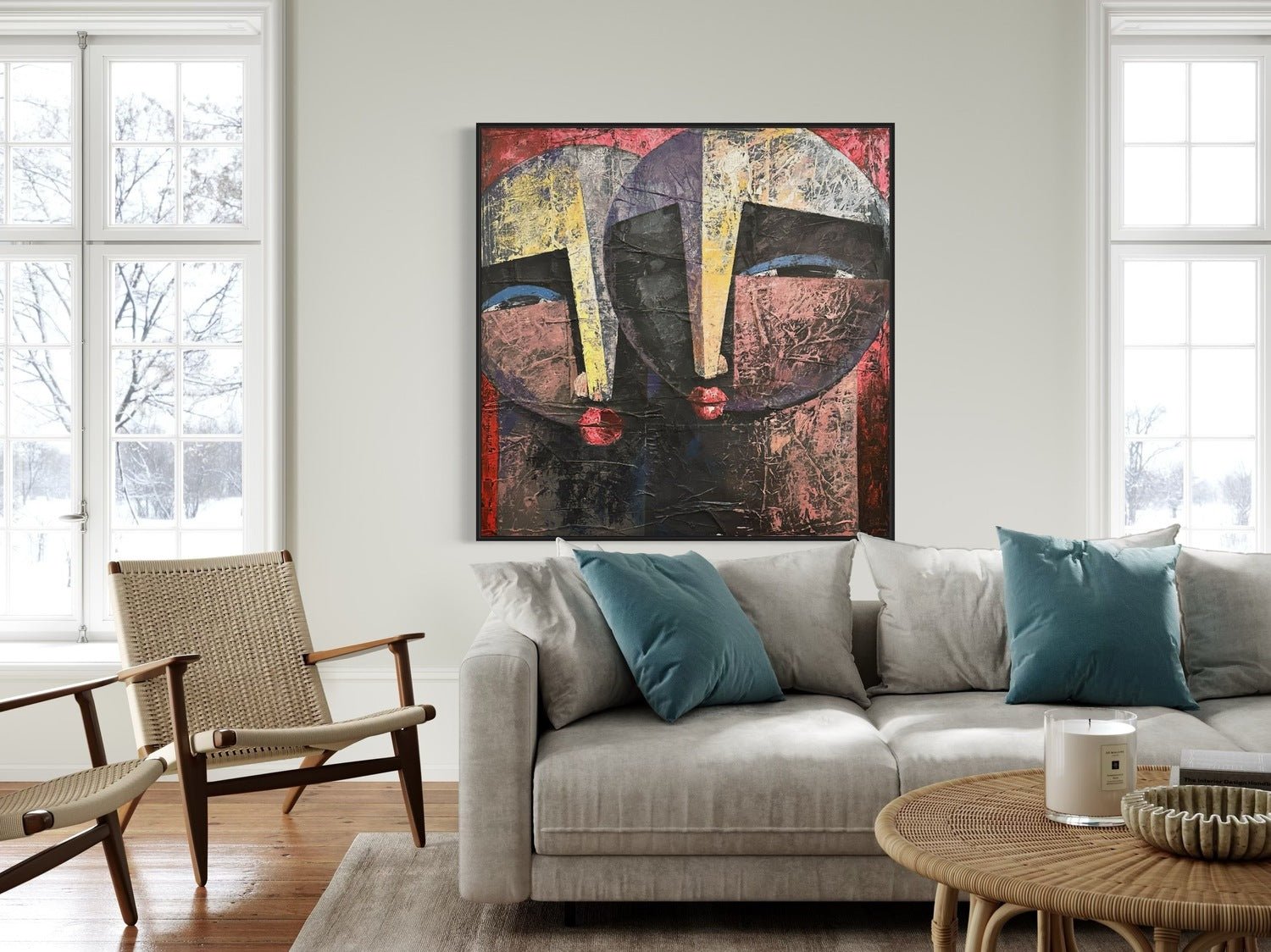 A modern living room with a light gray sofa, blue and beige cushions, wooden chairs, and a round coffee table. Above the sofa hangs "Eye Contact," a textured acrylic painting by Nigerian artist Christopher Ankeli.