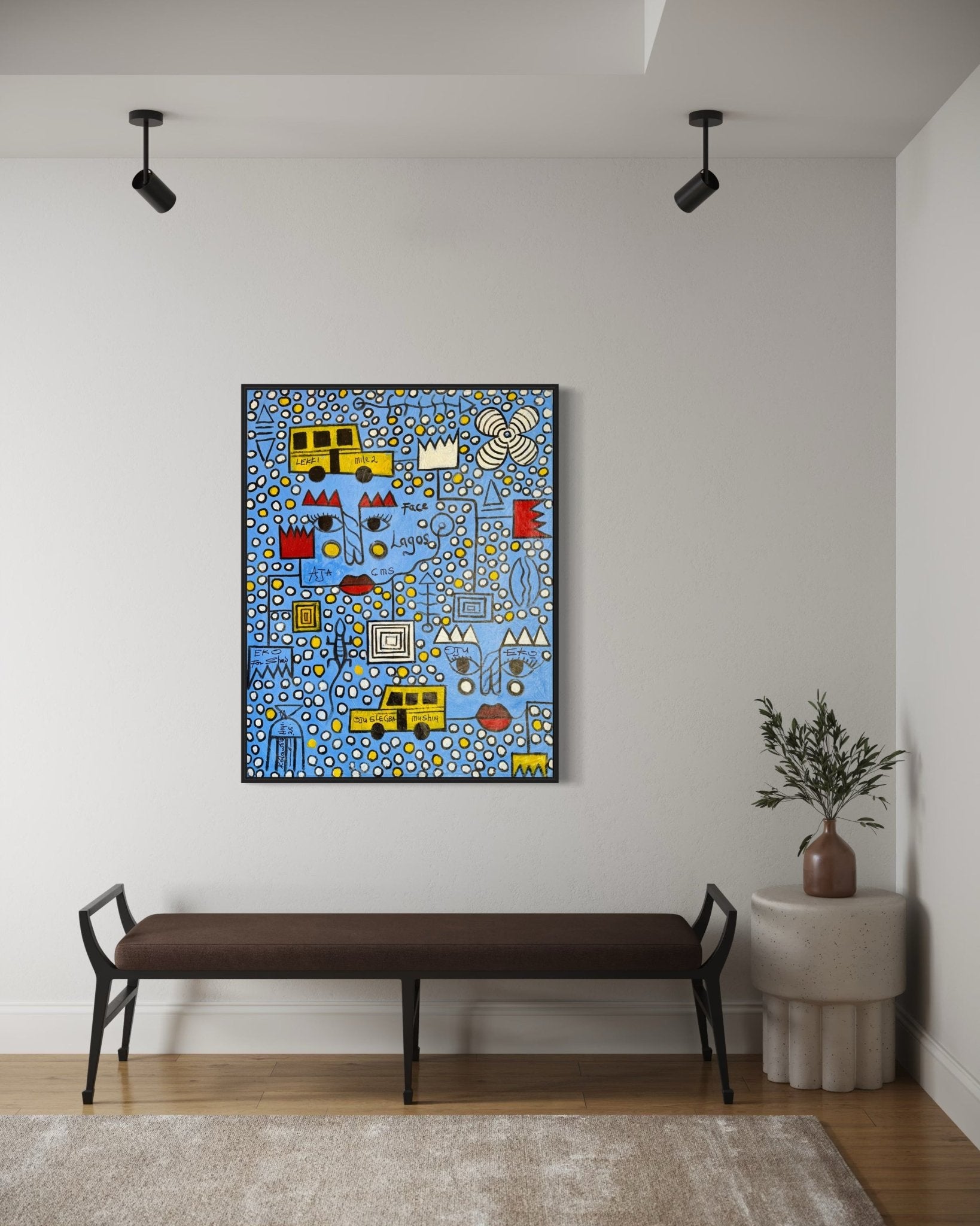 Face Of Lagos" by Kolawale Niyi—a vibrant abstract painting—hangs on a white wall above a brown bench. To the right, a small round table with a plant complements the scene, while a light rug covers the wooden floor.