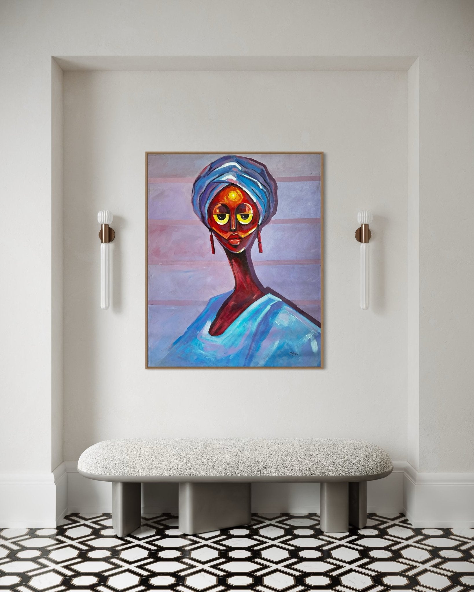 A modern hallway with a geometric black-and-white floor features a cushioned bench and ‘Gele Queen’ by Bibianna African Art Collective, a vibrant portrait of a woman in blue, centered between two wall sconces.