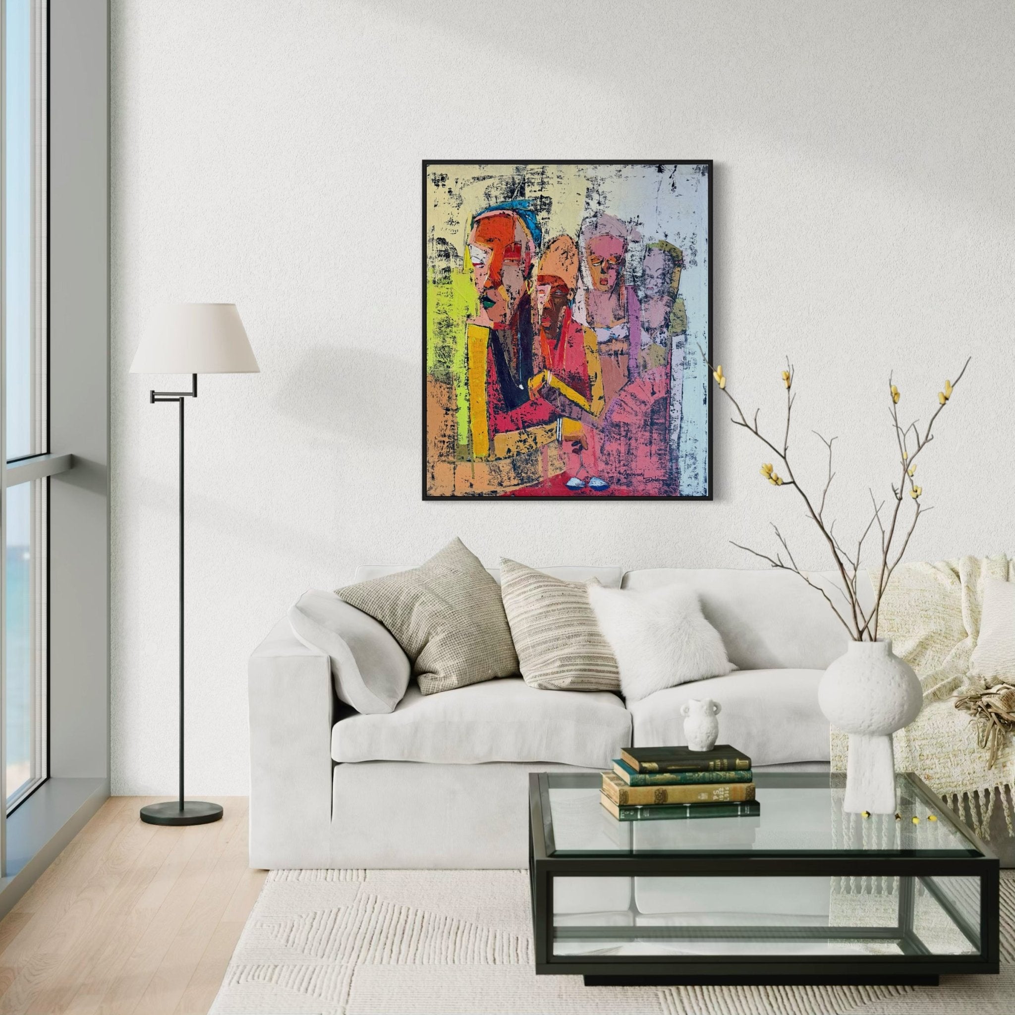 A modern living room with a white sofa, neutral pillows, and a glass coffee table sits beneath ‘Gender Equality,’ a vibrant hand-signed painting by Dolapo Ogunnusi from the UK. Sunlight through large windows highlights the unique artwork above the couch.