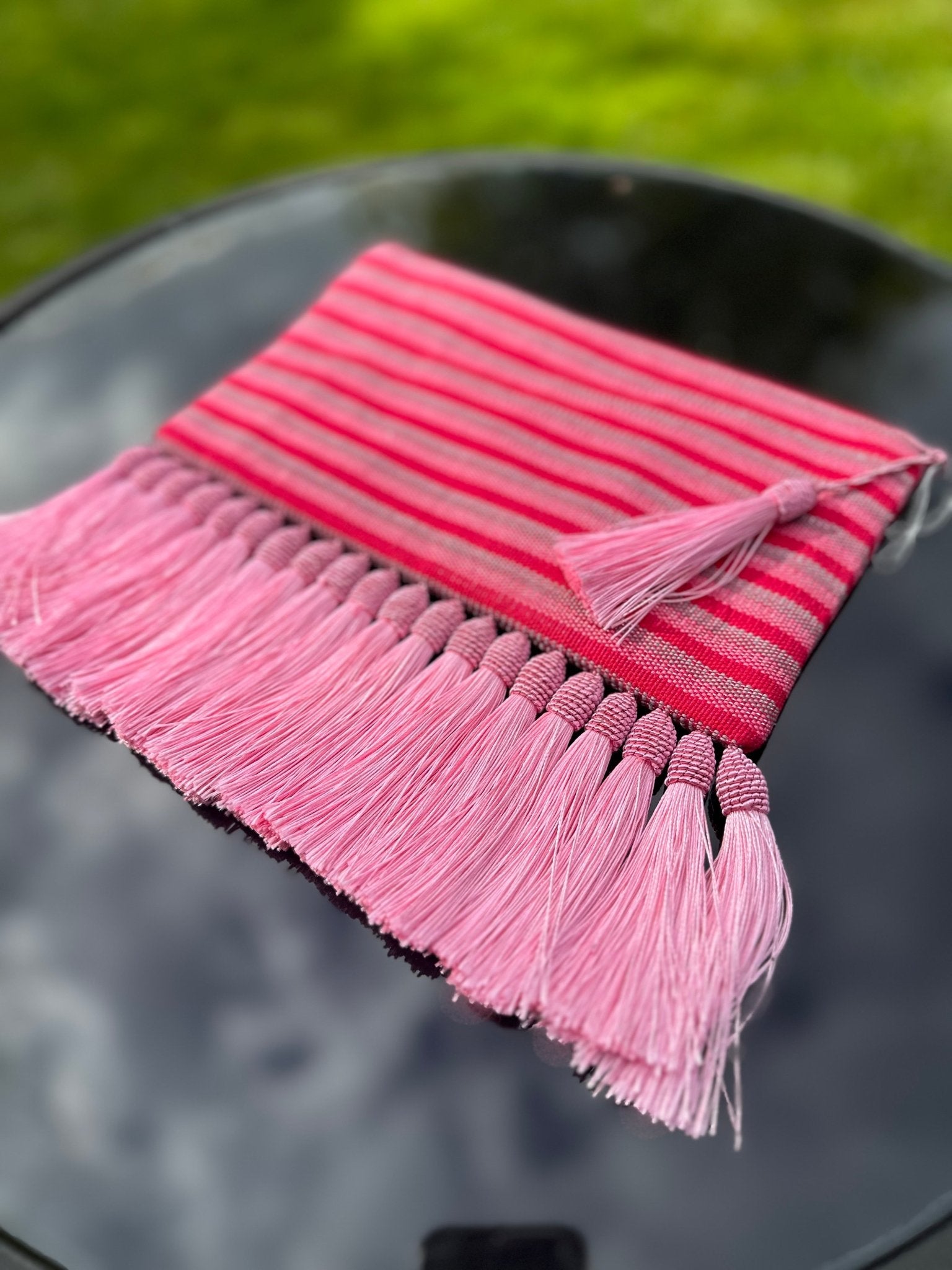 The Handmade Ashoke Tasseled Clutch by bibianna.co.uk features striking pink stripes and long pink tassels, making it a stylish occasion bag that's perfect for adding an eye-catching touch to any party look.