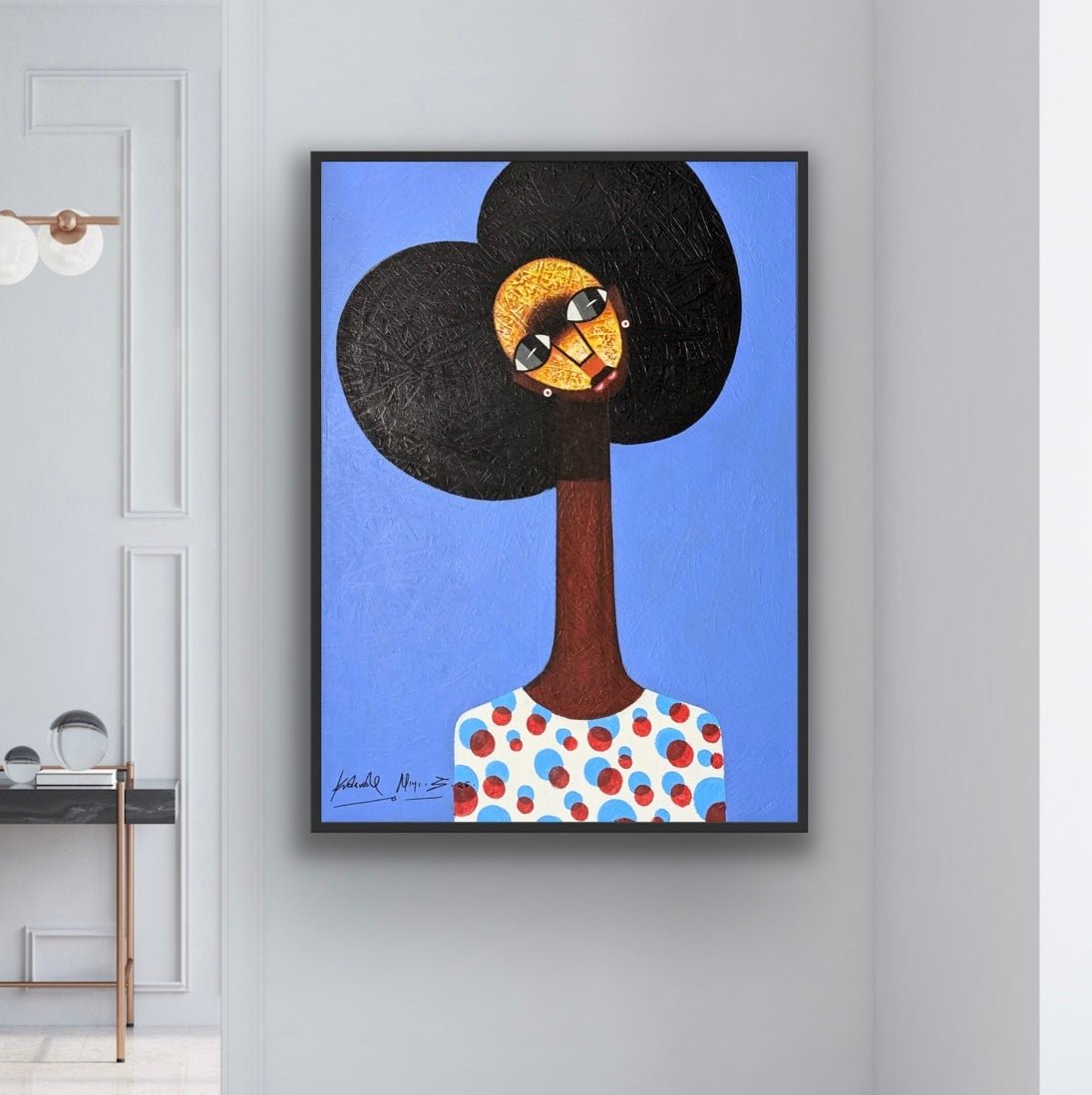 Kolawale Niyi’s Charming Cubist Portrait With Textured Details, a framed acrylic on canvas featuring a stylized figure with a large afro, long neck, and patterned shirt on blue, decorates a light gray wall in a modern space.