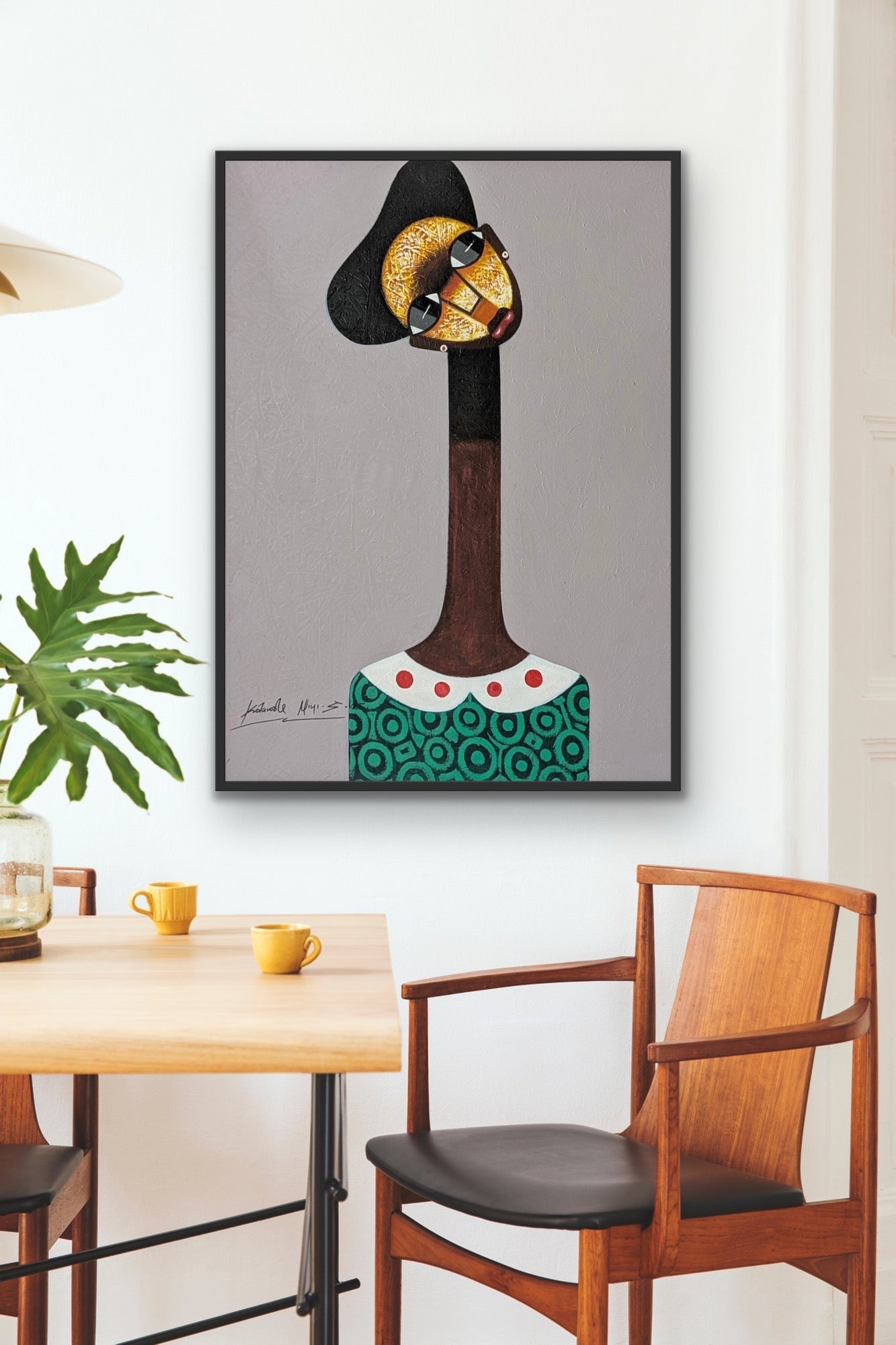 A modern dining area features wooden chairs, a table set with yellow cups, and the Kolawale Niyi Cubist Portrait by Kolawale Niyi—an abstract, hand-signed work depicting a long-necked figure in sunglasses, hat, and patterned green shirt.