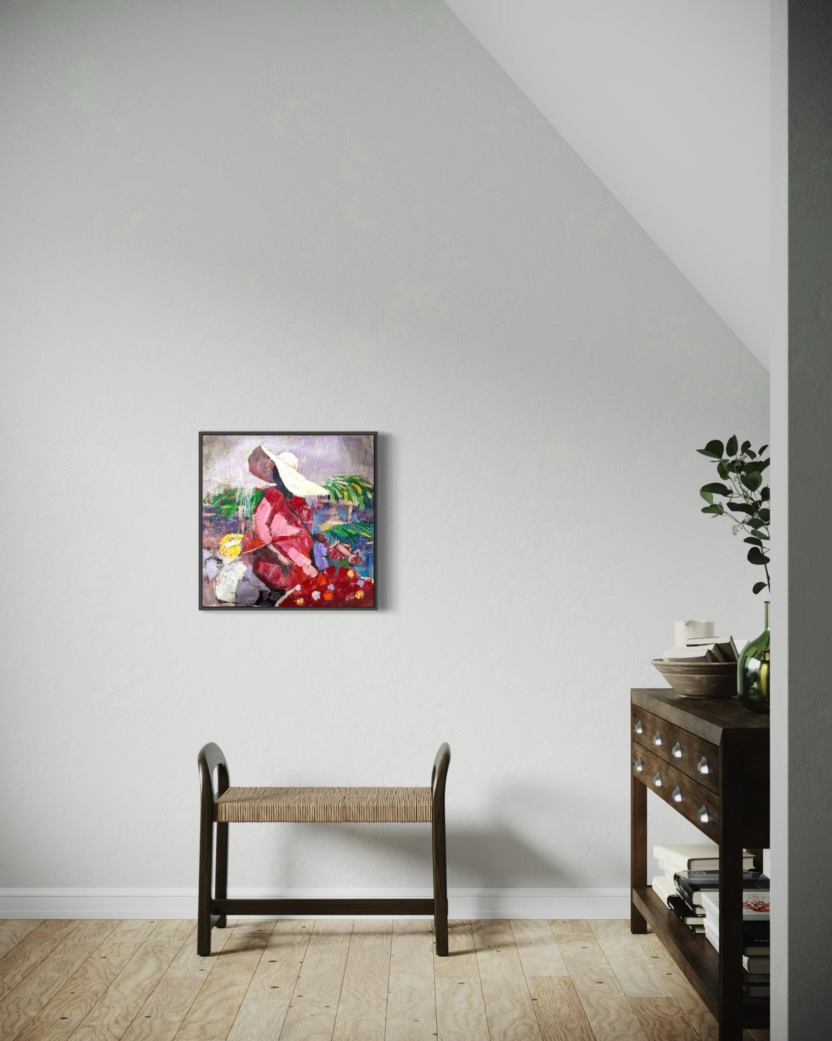 A minimalist room features a woven bench, a wood console with plants and decor, and "Market Sance" Lady In Sun hat by NOSA OSADOLOR—an original acrylic painting of a lady in sun hat with birds, on a sunlit white wall.