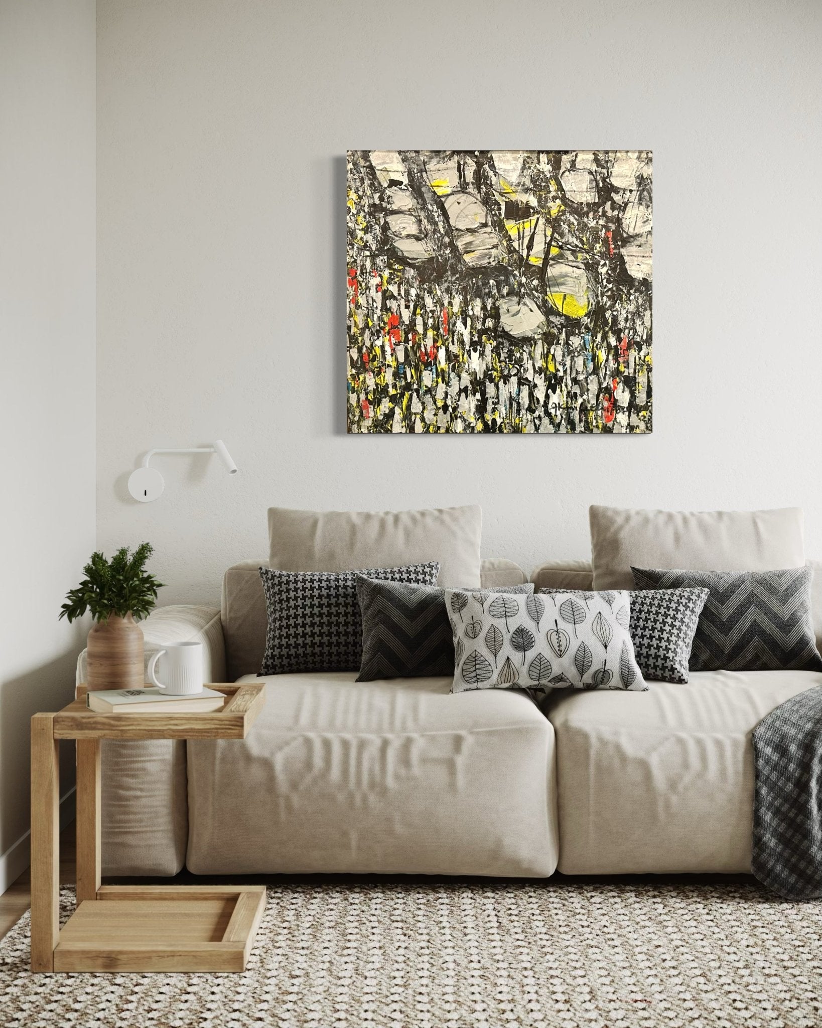 A beige sofa with patterned cushions sits against a white wall, topped by "Making Our Way Home," an original Akhile Ehiforia painting of a Nigerian street market at rush hour. A wooden side table with a plant, cup, and book sits beneath a wall lamp.