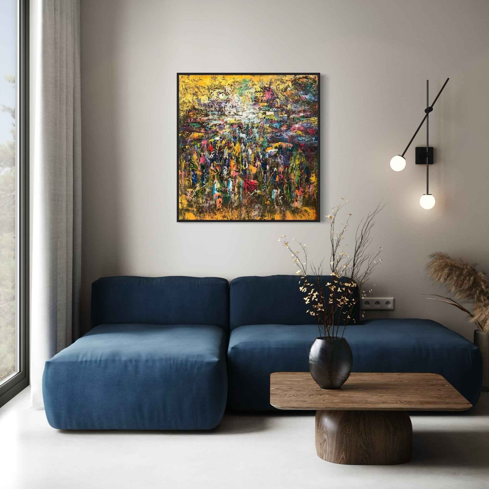 Modern living room with a blue sofa, wooden coffee table with a black vase and dried branches, wall-mounted light fixture, and "Market" by J.O. Aransiola displayed above the sofa. Natural light streams in from a large window.