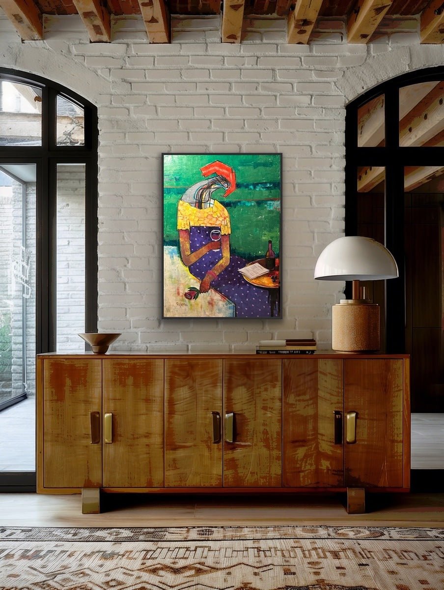 A modern room features a wooden sideboard, decorative items, and a white lamp beneath “Masturdating 5,” a figurative abstract acrylic on canvas from Akintoye Segun-Shiigo's Serene Reflections collection, set against a white brick wall with large black-framed windows.