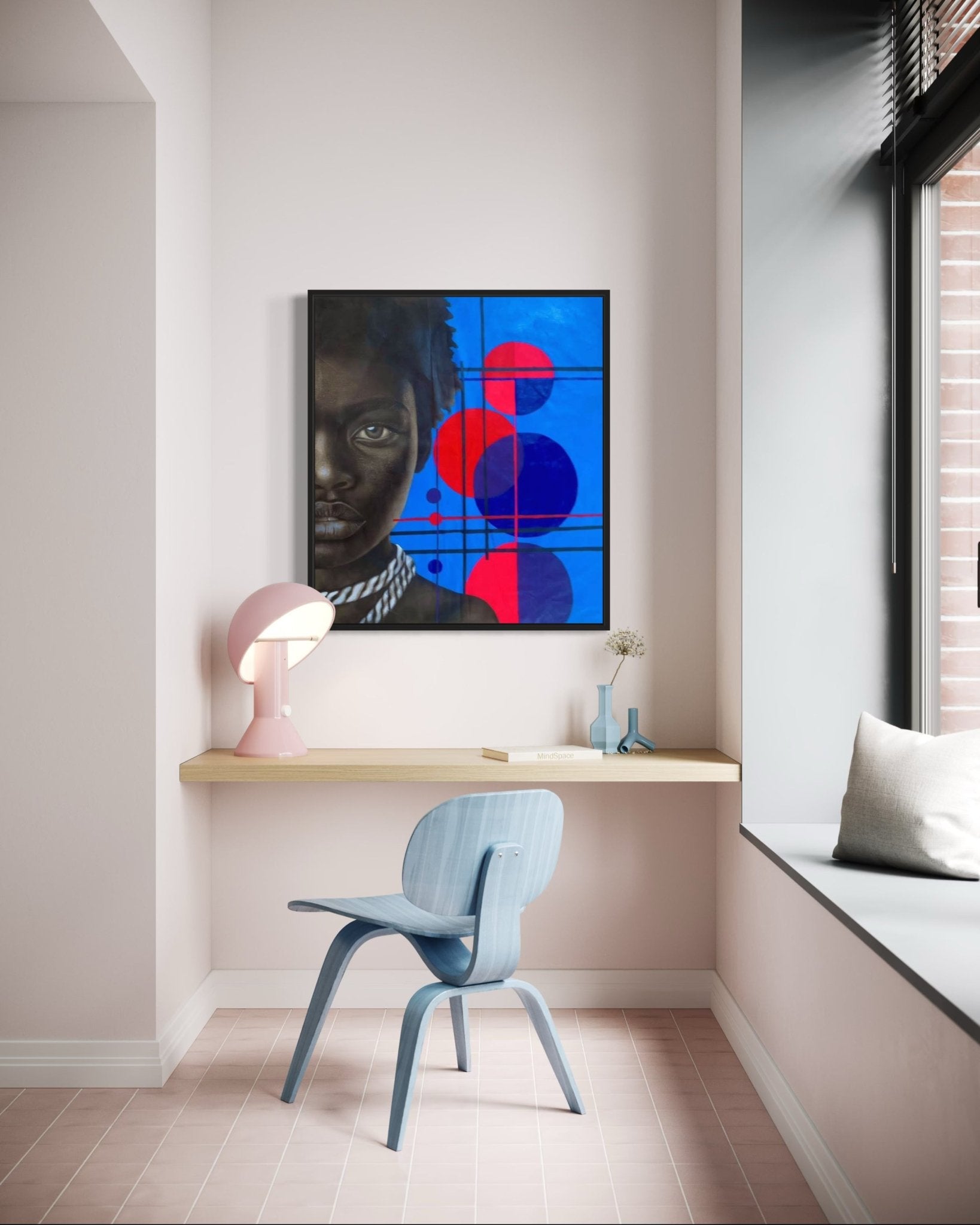 A modern minimalist workspace with a light wood floating desk, blue chair, pink lamp, and window seat. Above the desk hangs 'Mindset' by Taiwo John Afuye—a hand-signed painting with bold blue and red geometric shapes.