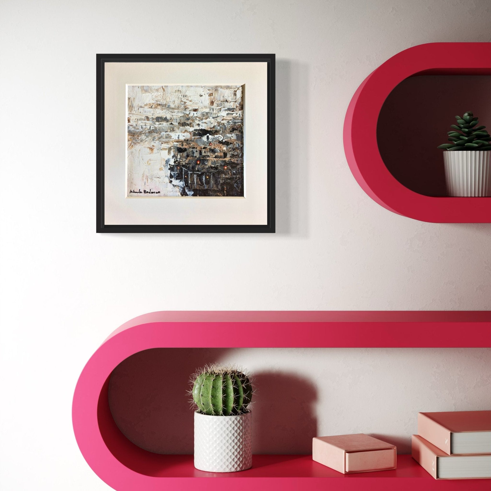 The Miniature Abstract Landscape Kehinde Badmus by Kehinde Badmuss, a hand-signed acrylic painting on canvas, is framed and displayed above pink curved shelves with a cactus in a white pot, a plant, and several closed books.