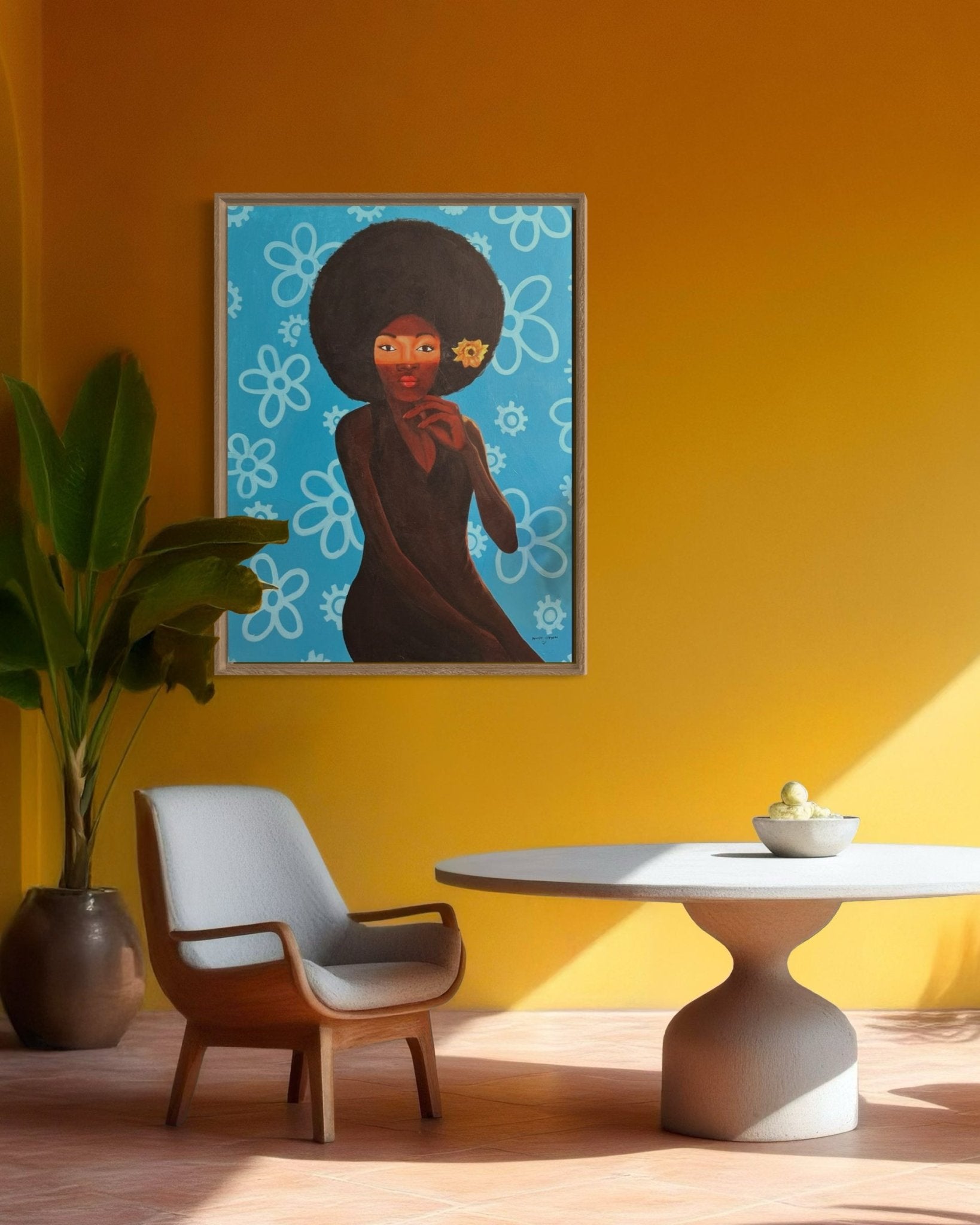 A modern room with a yellow wall features "My Afro 2," a hand-signed framed acrylic painting by Afuope Opeyemi, alongside a large potted plant, gray lounge chair, and round table with lemons. Sunlight streams in, casting shadows.