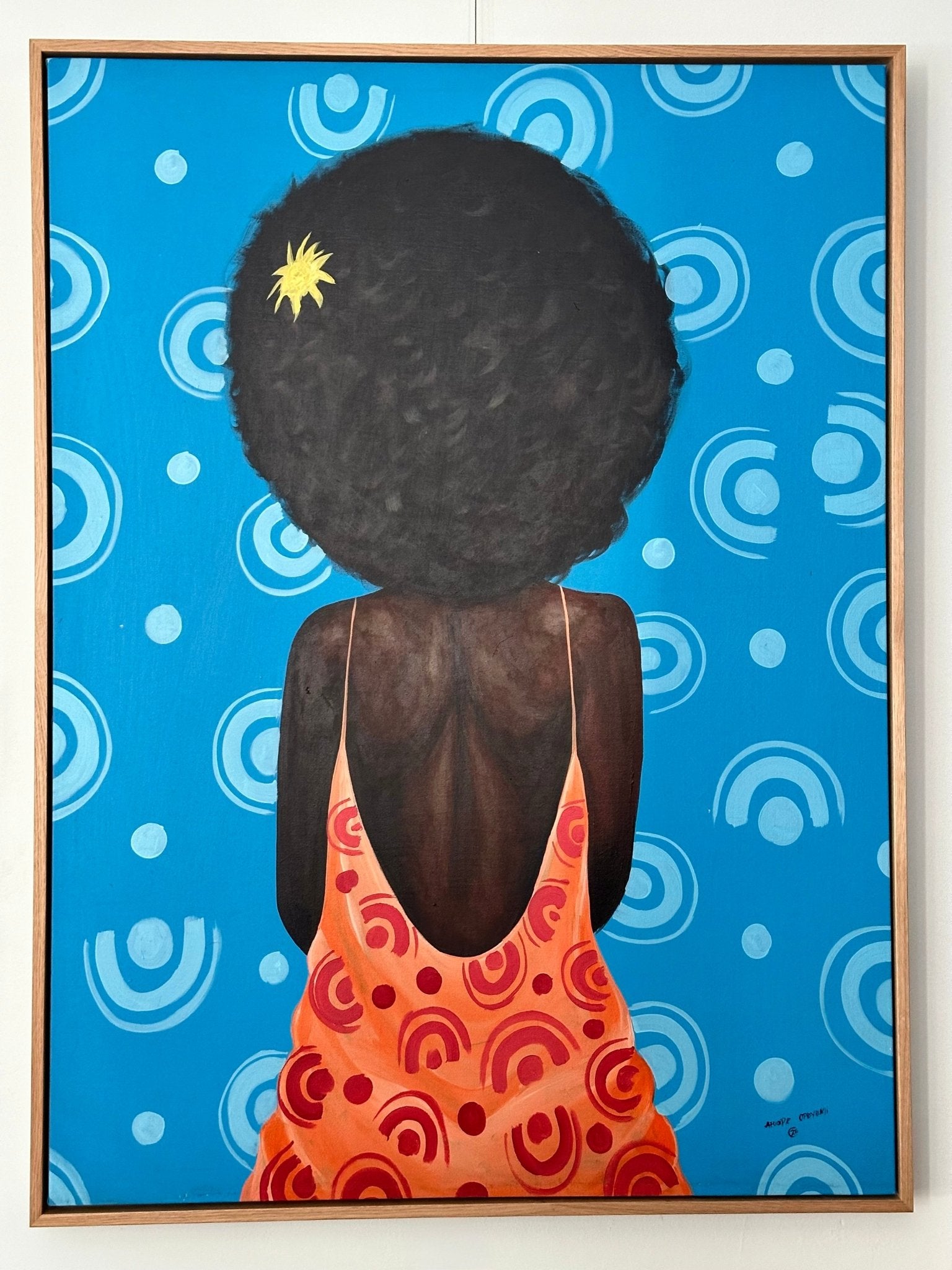 My Afro" Retro Portrait by Afuope Opeyemi is an acrylic on canvas artwork showing a woman with a large afro adorned with a yellow flower, wearing an orange dress with red swirls, set against blue and white geometric shapes.