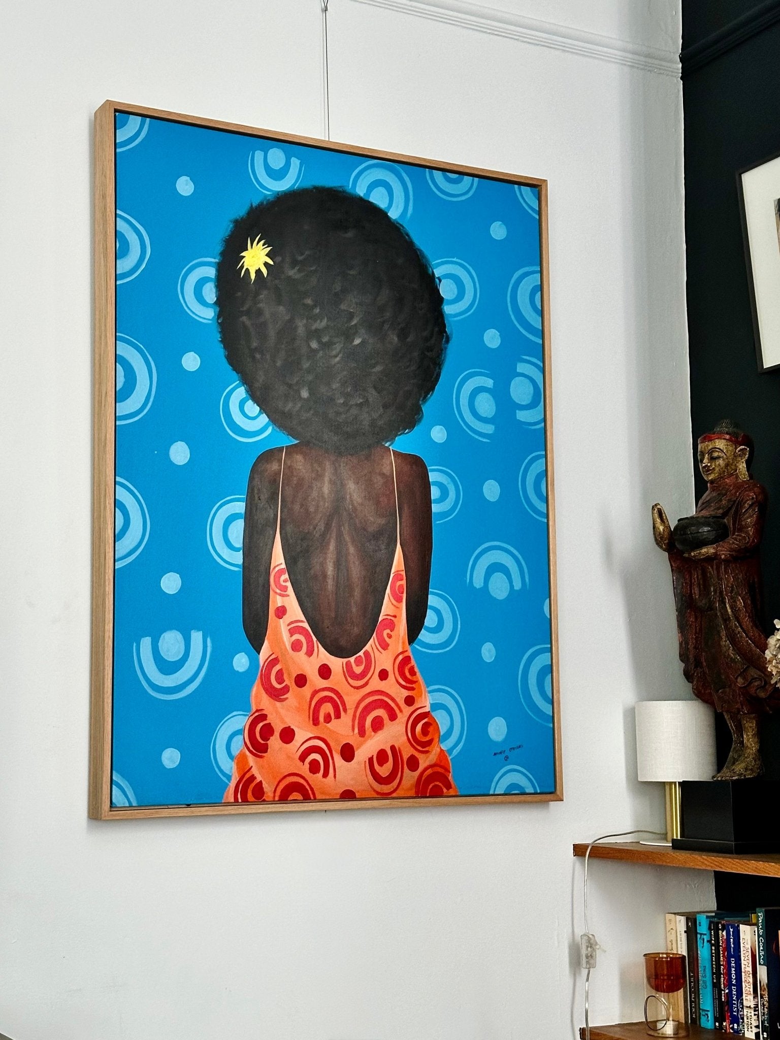 “My Afro” Retro Portrait by Opeyemi, an acrylic on canvas from Afuope Opeyemi, shows a dark-skinned figure with curly hair in a red-orange low-back dress against a bright blue circular-patterned backdrop—a standout of contemporary African art.