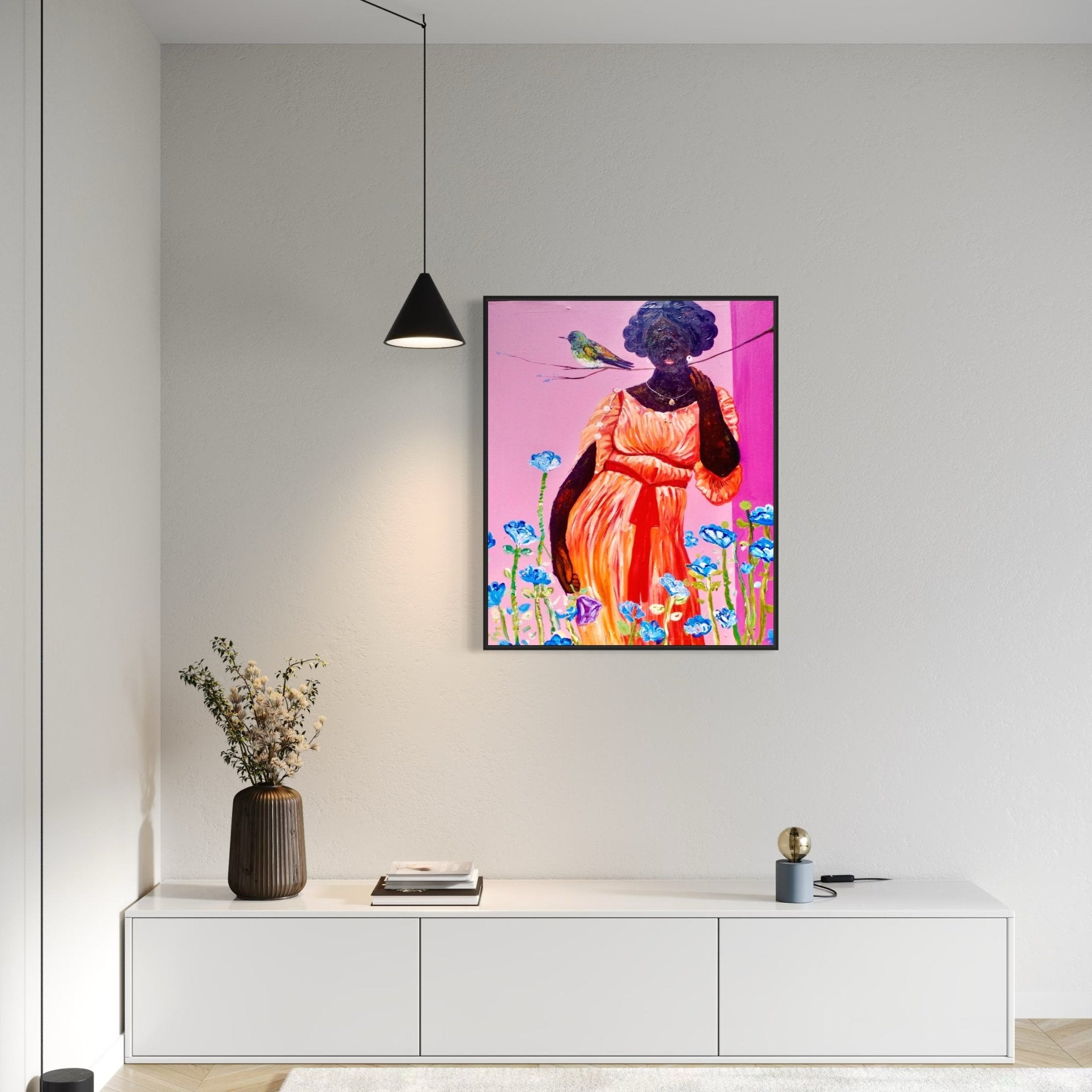 A modern living room features a white cabinet with decor and the Olajide Kuti – Woman with Bird, Acrylic on Canvas by Ola Kuti, a vibrant painting of a woman in an orange dress with flowers and a bird, illuminated by a black hanging lamp.