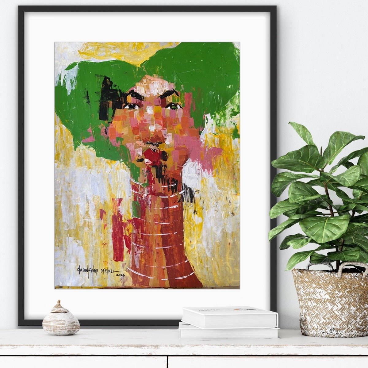 Acrylic on paper from the "One of a Kind Series" by Olasunkanmi Oyelusi, featuring bold green and yellow brushstrokes and a long-necked figure, framed and displayed above a table with decor.