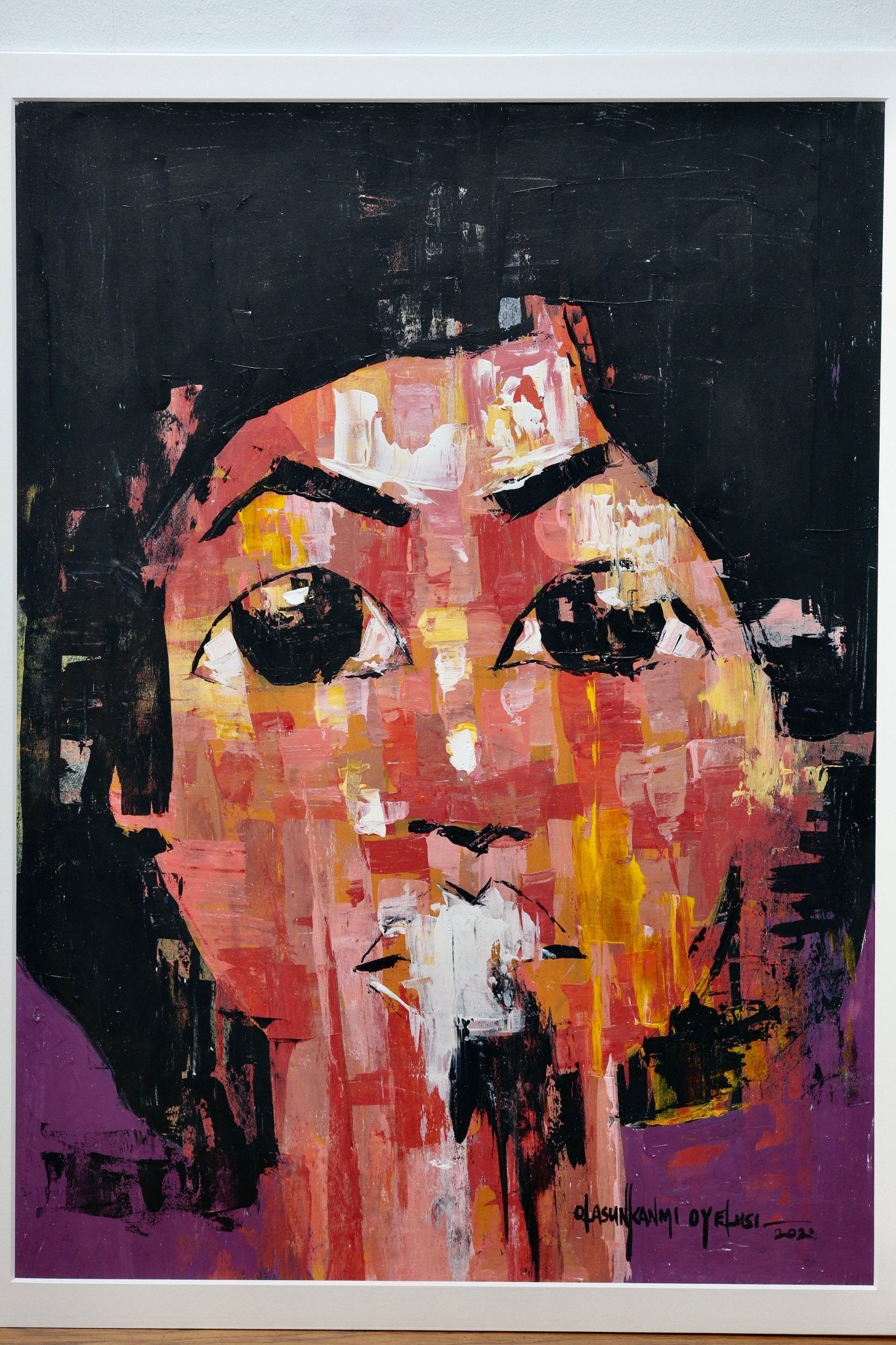 From the "One of a Kind Series" by Olasunkanmi Oyelusi, this original acrylic painting features a bold abstract face with striking black eyes and vivid strokes of red, orange, yellow, black, and purple on paper—ready to be framed.