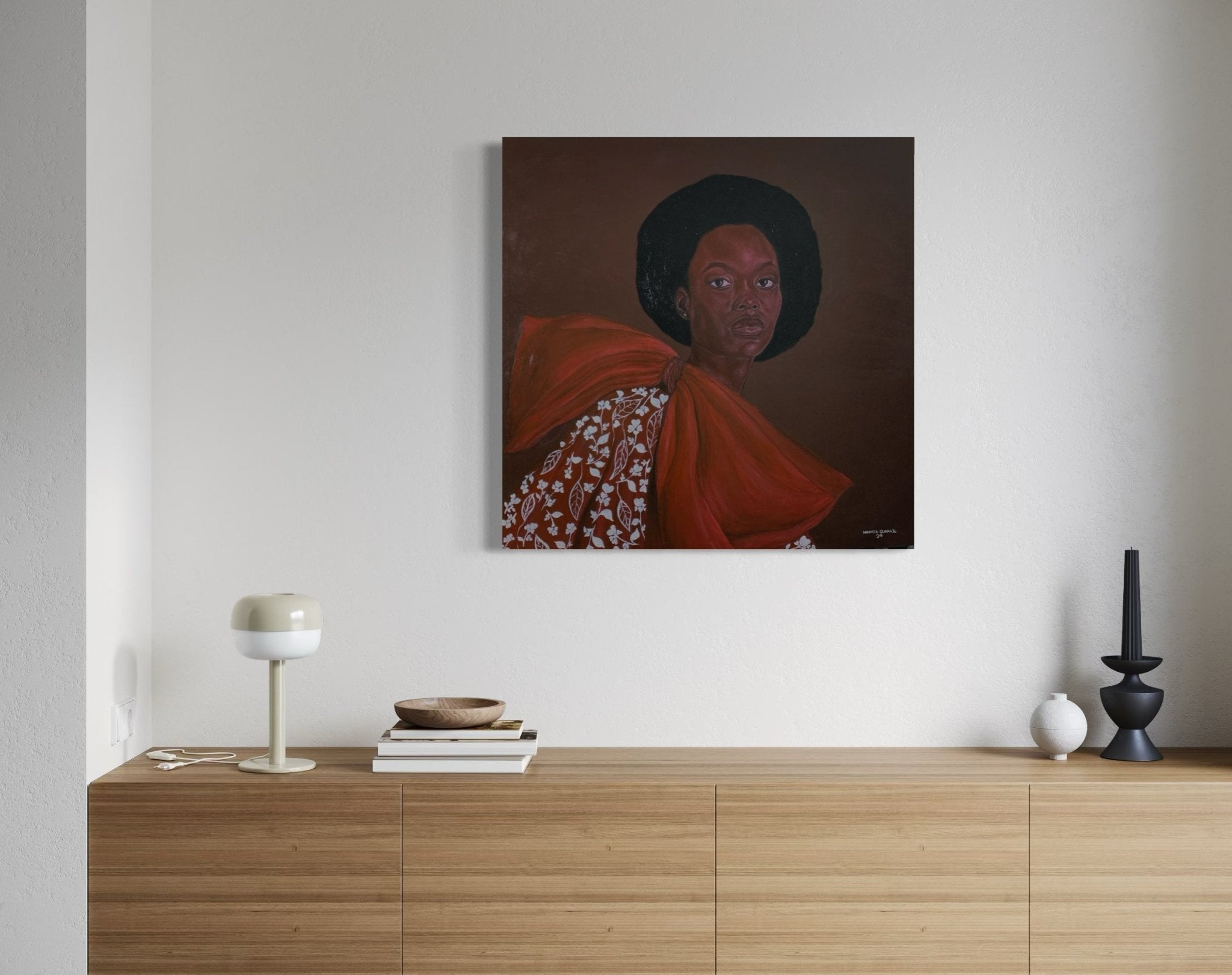 A modern wooden sideboard with books, decor, and a lamp sits beneath Portrait by Hammed Omobayo (Hammed Olayanju Omobayo) on a light wall. Two small stools are placed in front of this striking artwork featuring a woman in a red dress with an afro.
