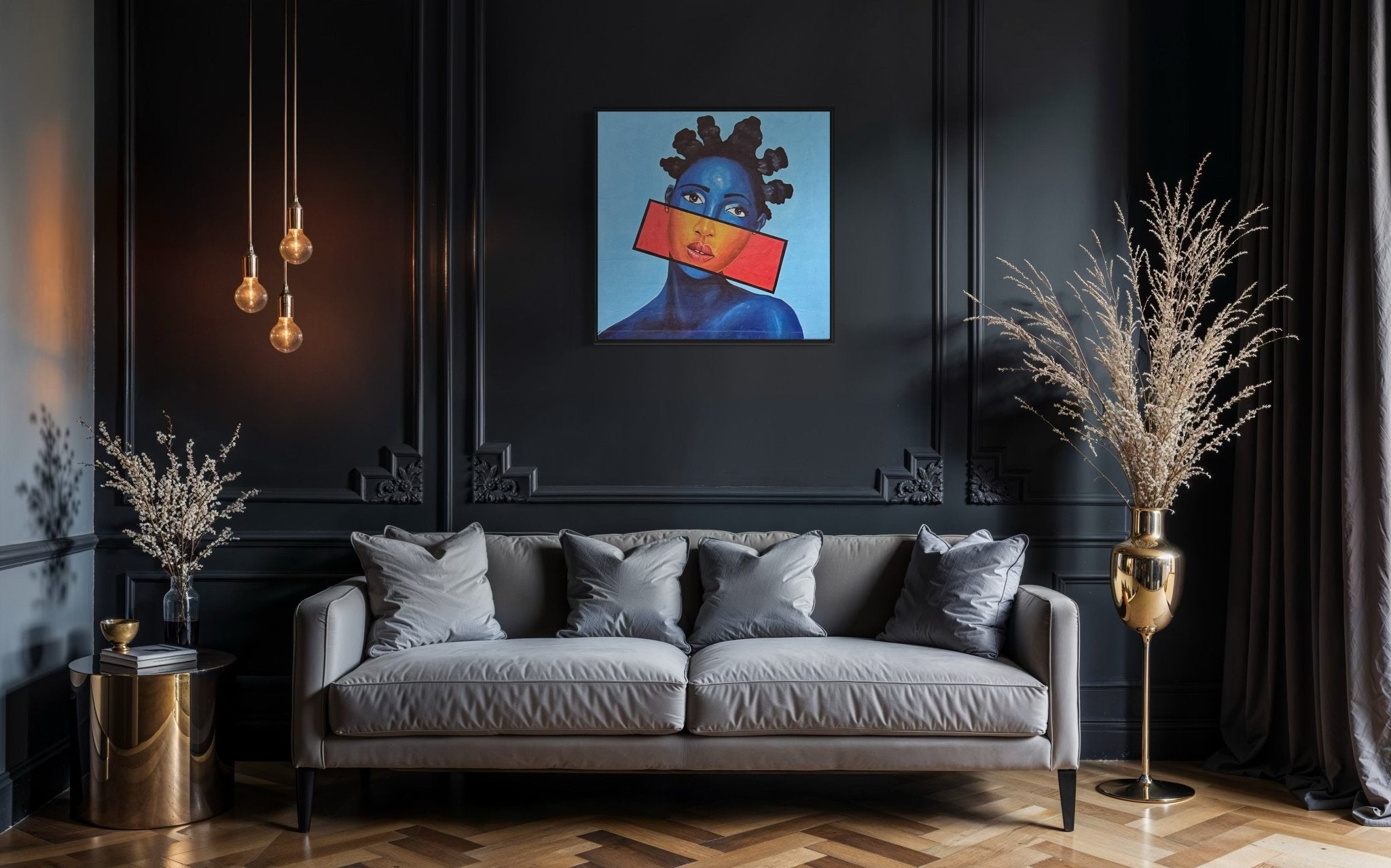 A modern living room with dark walls, a gray sofa, and gold tables features "You Can't Silence Me," an acrylic on canvas portrait of an African woman by Afuope Opeyemi, hanging above the sofa. Vases with dried plants complete the look.