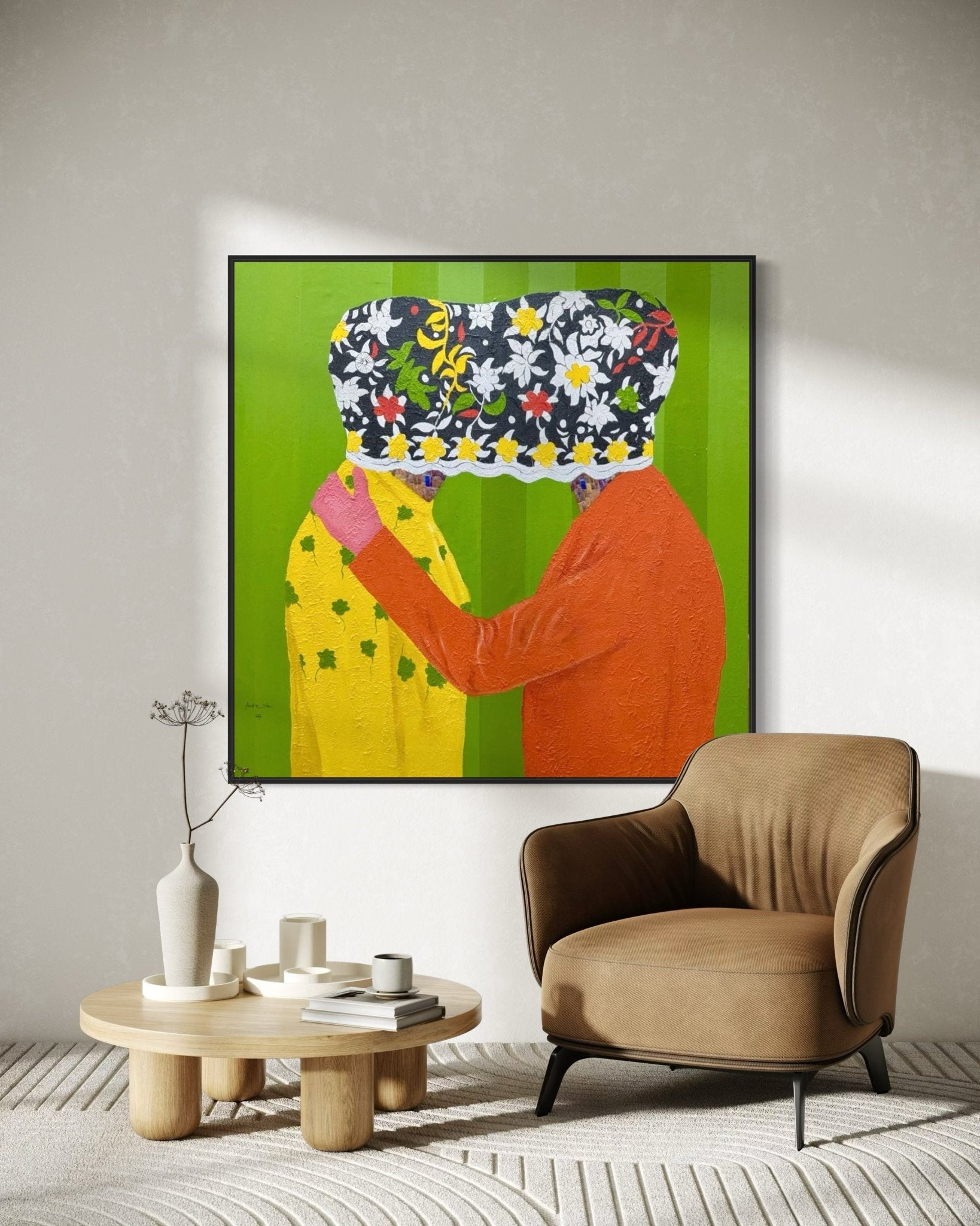 A modern living room features a tan armchair, a round table with vases, and Slam Austin's "Secrets" (122 x 122cm), an acrylic on canvas artwork of two embracing figures with floral-patterned cloths over their faces against a green backdrop.