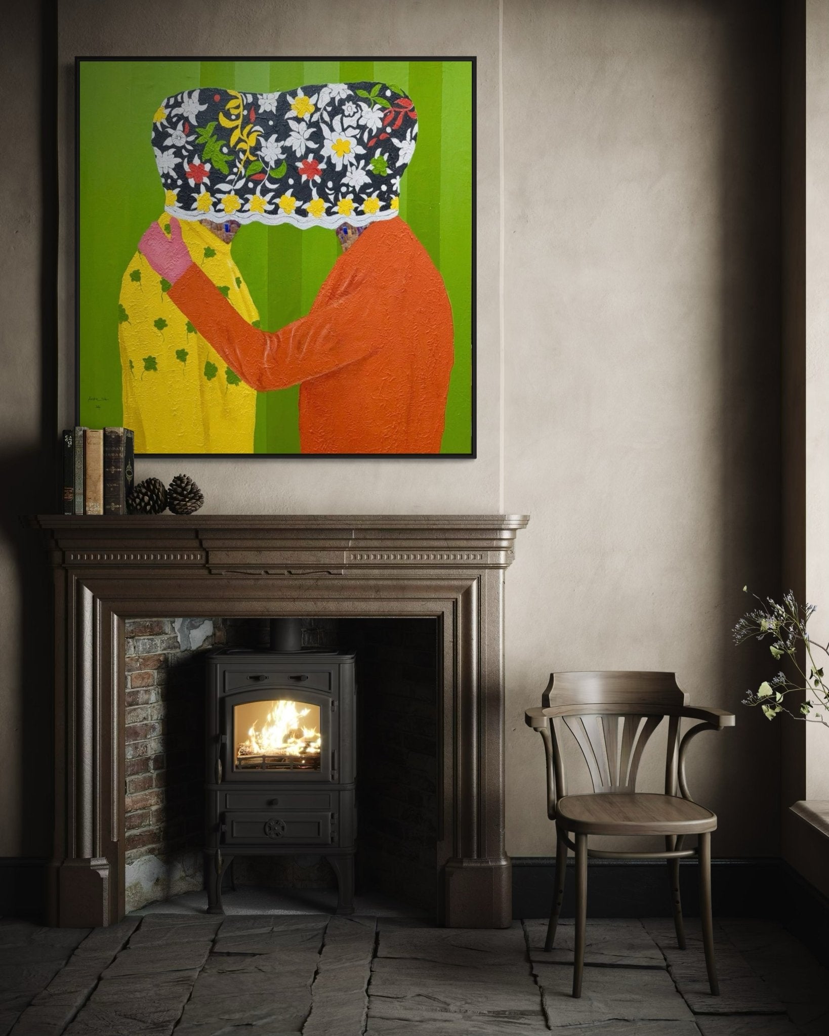 A cozy room with a wood stove, empty wooden chair, and mantelpiece displays "Secrets" (122 x 122cm) by Slam Austin above it—an acrylic painting of two people embracing, their faces obscured by patterned cloth.