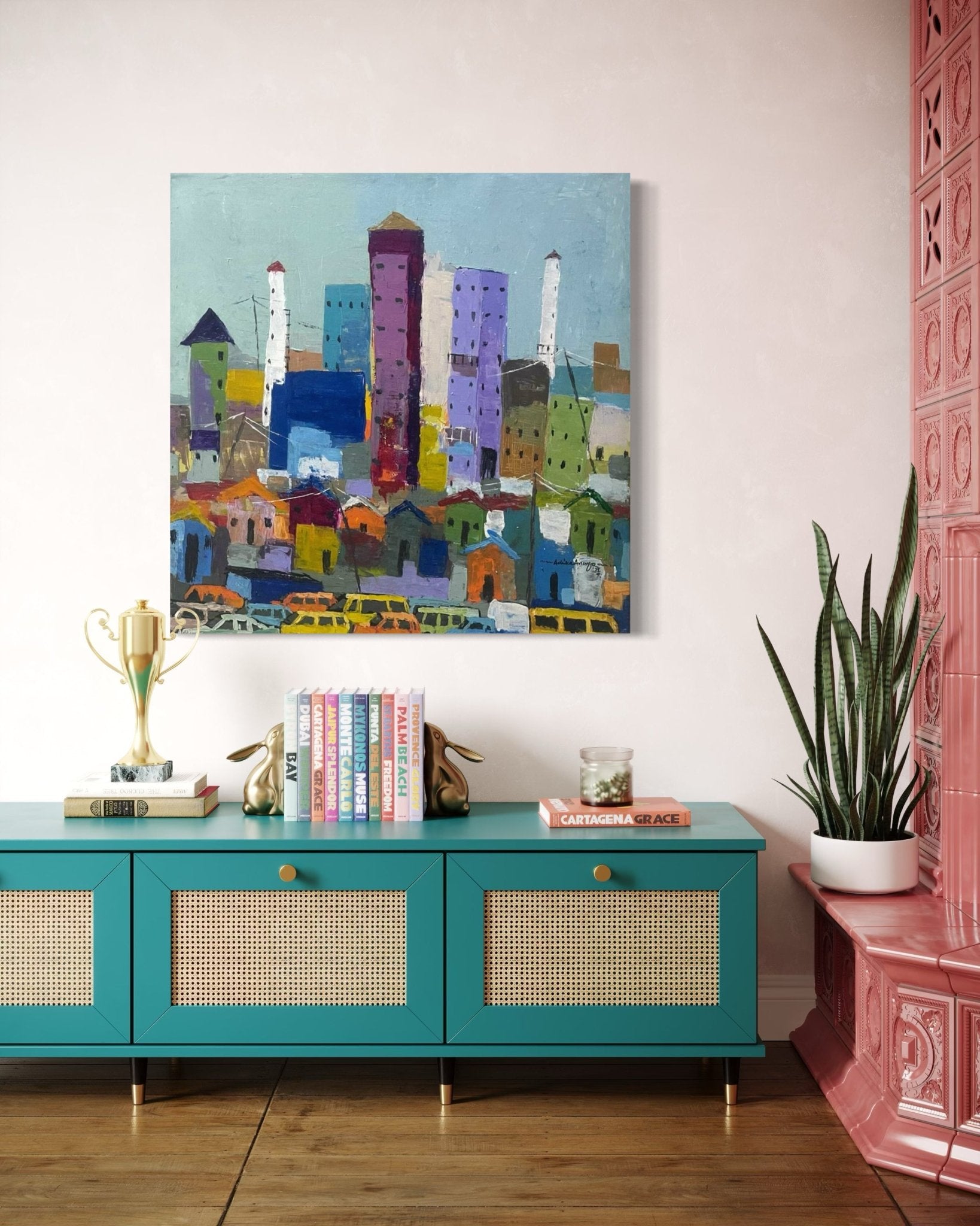 A modern living room with a teal sideboard, plant, and trophy features 'Somewhere In Lagos City' by Achike Anayo—a colorful cityscape painting with certificate of authenticity—on a pale pink wall beside pink decorative tiles.