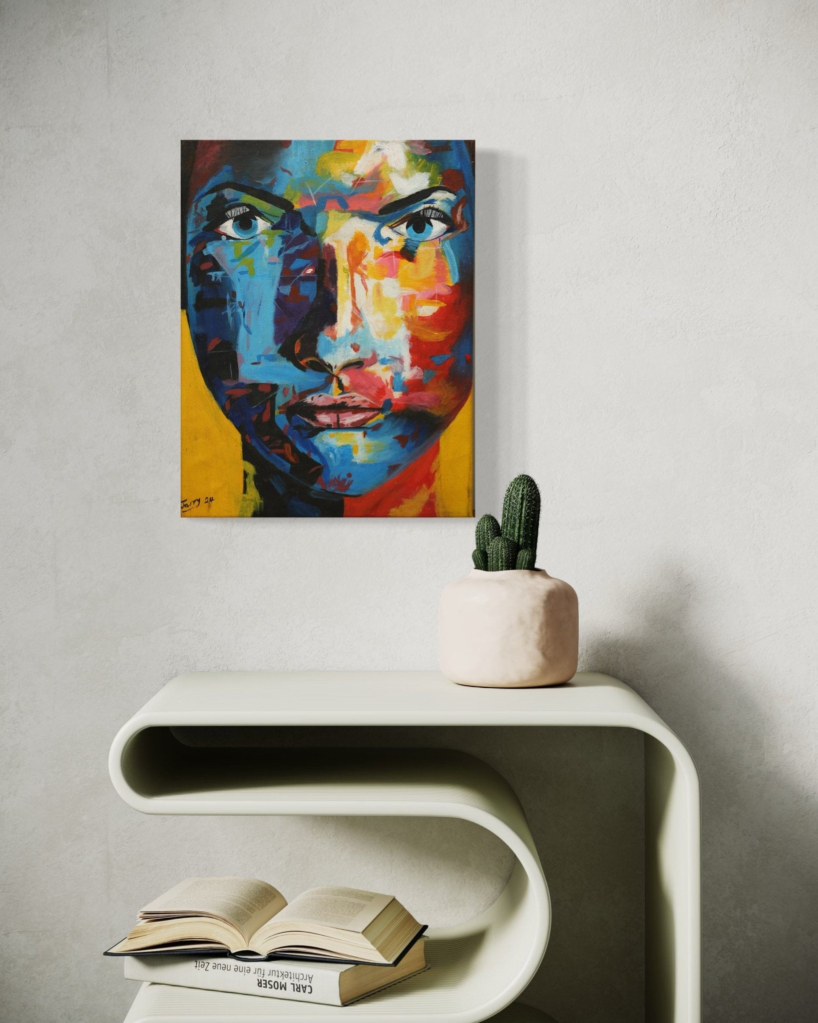 The Acrylic on Canvas Colourful Miniature Portrait "Colour Of Beauty" by Ademola Jerry, hand-signed by the artist, hangs on a light wall above a modern curved shelf with a potted cactus and an open book.