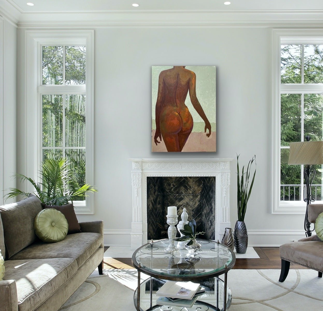 A bright living room with large windows, a beige sofa, and a fireplace features "The Temple" Tasteful Painting Nude by Faith O Sidneu above the mantle. Green plants and modern decor finish the look.