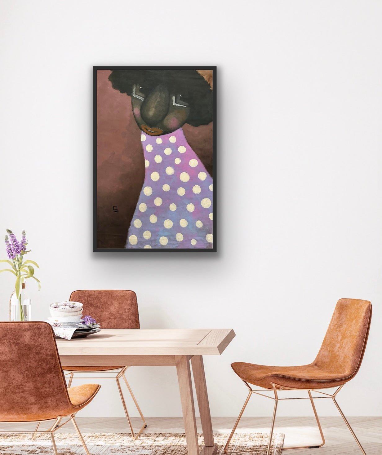 A modern dining area with a light wooden table, four brown suede chairs, and "Untitled" Contemporary Portraiture by Prince Obasi—an acrylic abstract of a large-nosed person with black hair in a purple polka-dot outfit on a white wall.