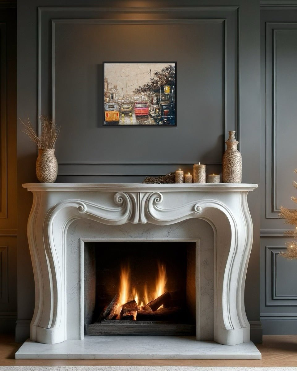 Elegant white fireplace with carved details, fire burning inside, vases and candles on top. Above hangs "These City Streets" Urban Street Scene Painting With Vintage Cars by Adewale Adeniyi on the gray paneled wall.
