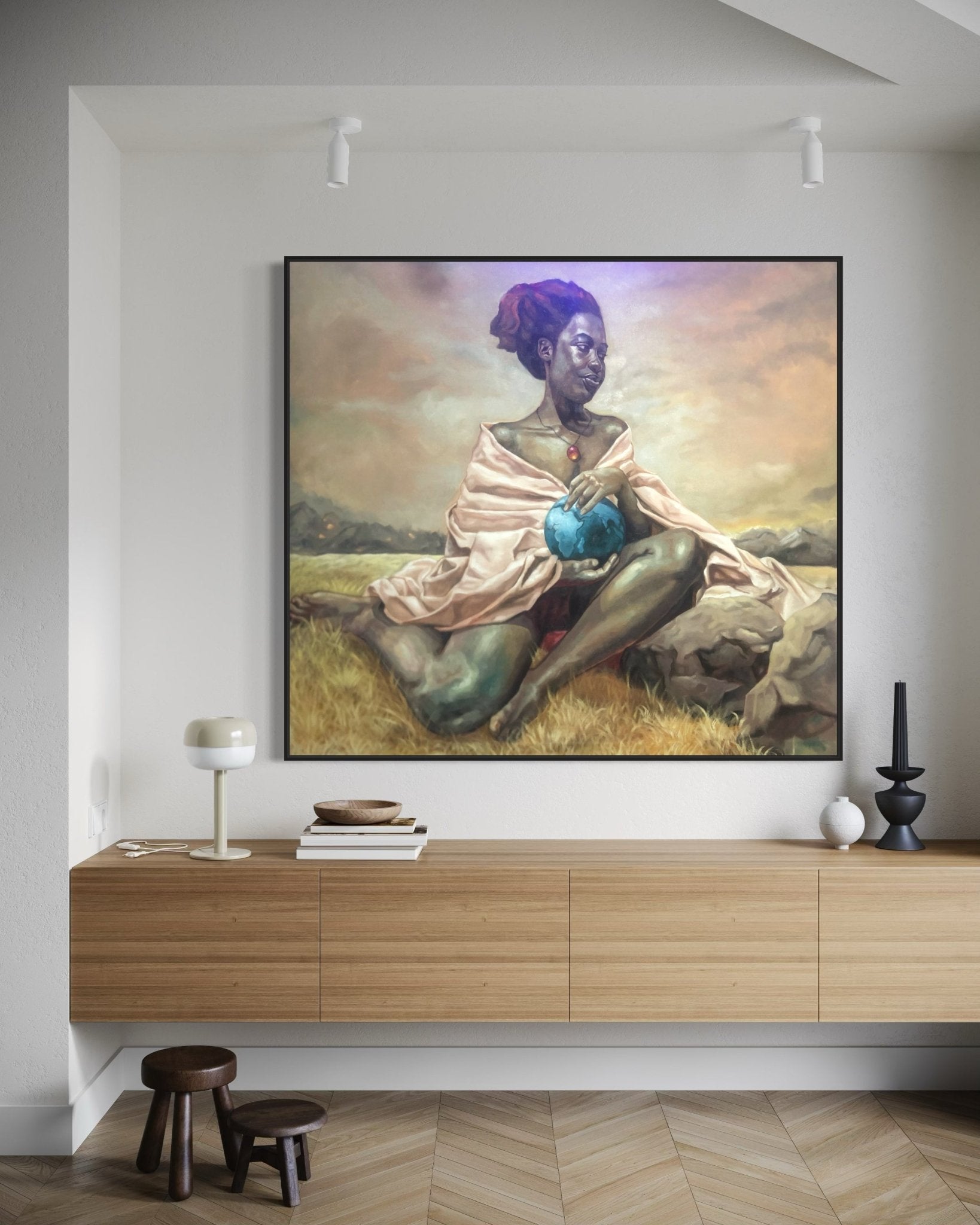 A large painting of a seated woman with dark skin and a red headwrap hangs above a modern wooden sideboard in a minimalist living room. The woman holds a blue vase and sits on grass under a dramatic sky.
