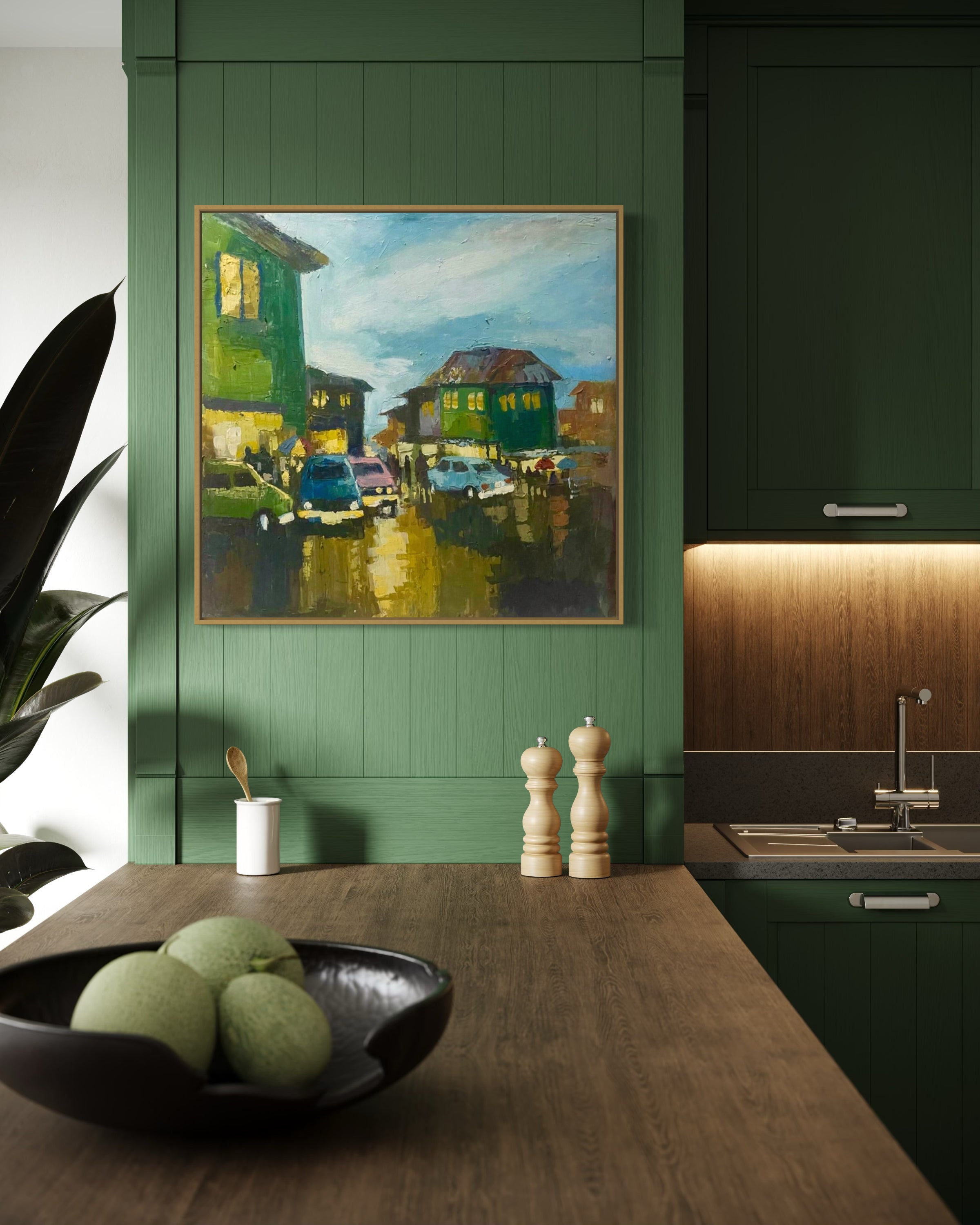 A modern kitchen with green cabinets, a wooden countertop, green fruits, grinders, a small plant, and 'Somewhere in Ibadan' by Pitar Alakhume—a framed original artwork with certificate—hanging on the wall.