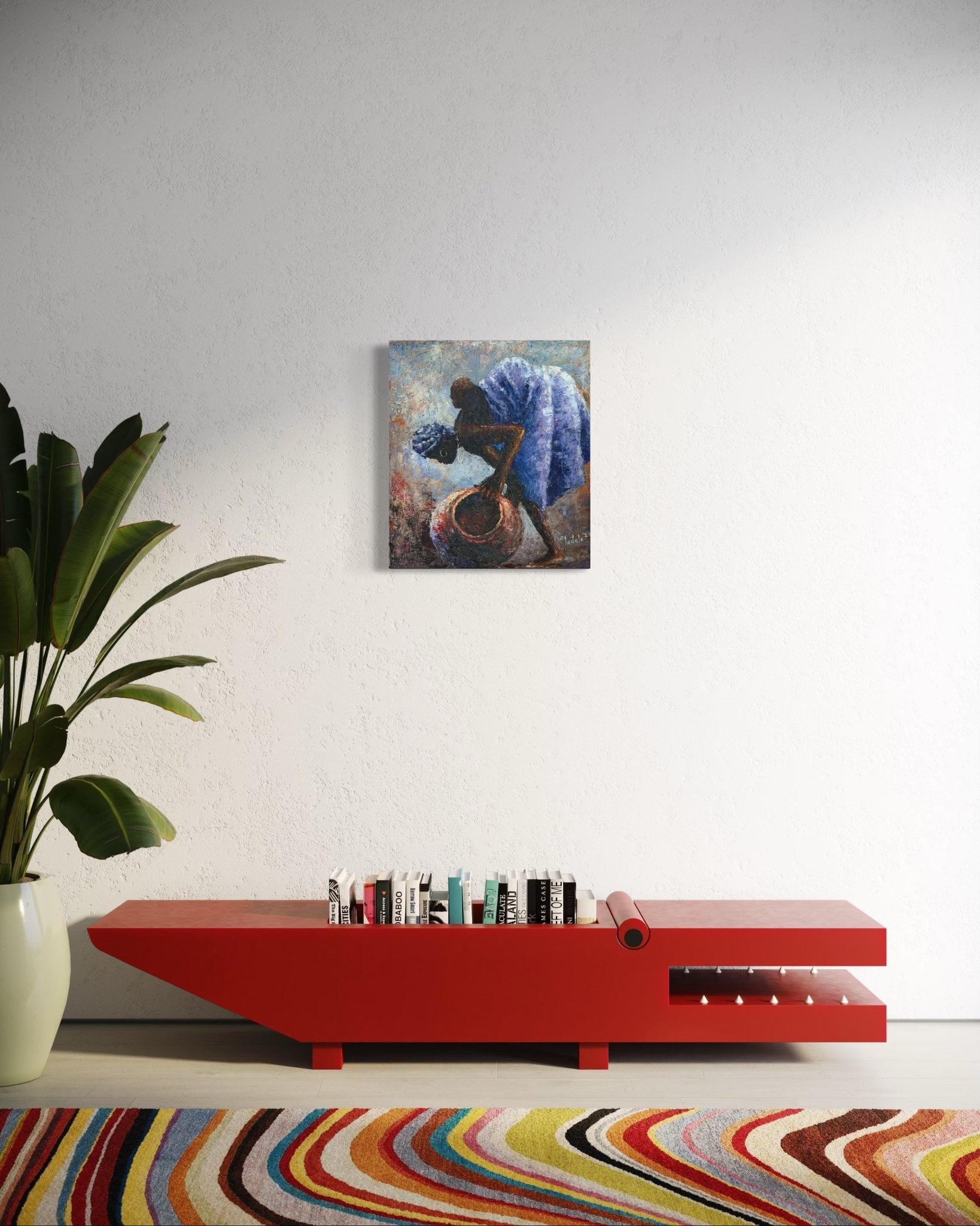 A modern living room features a red low bench with books, a large potted plant, a colorful wavy-patterned rug, and "Backed Up," an original framed painting by Sunday Oladele, inspired by Nigerian art, on a white wall.