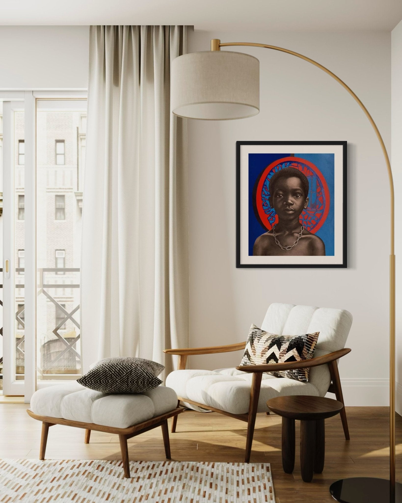 A modern living room features a cream armchair, ottoman, pillows, floor lamp, and side tables. The wall showcases "Chain Of Trauma II," an acrylic on board portrait with red halo by Taiwo John Afuye. Light pours through large windows.