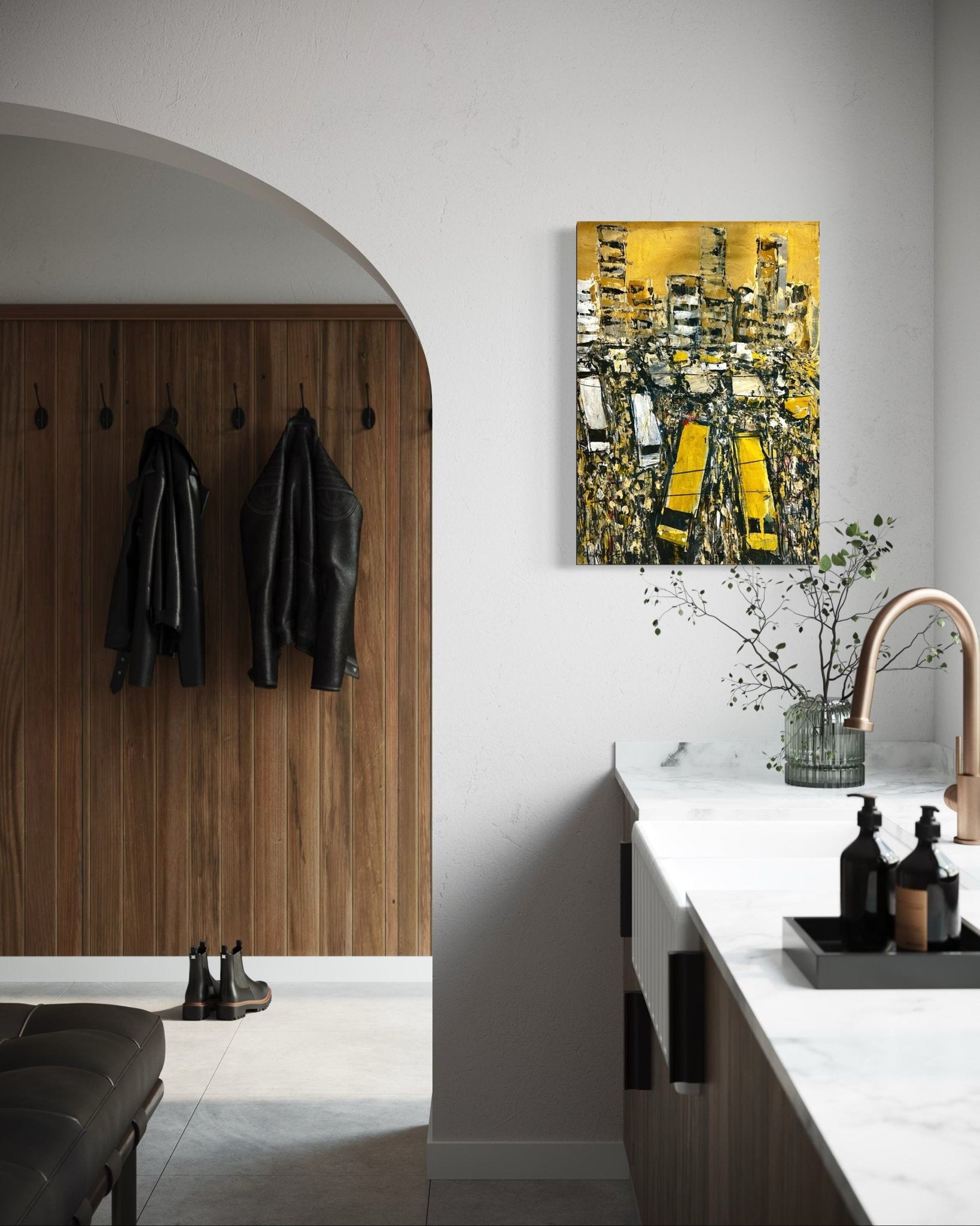A modern kitchen with a marble countertop, gold faucet, decorative bottles, and a "Danfo Life Lagos City" painting by Akhile Ehiforia featuring yellow taxis above the counter. Black jackets and boots hang on a wooden wall by an arched doorway.