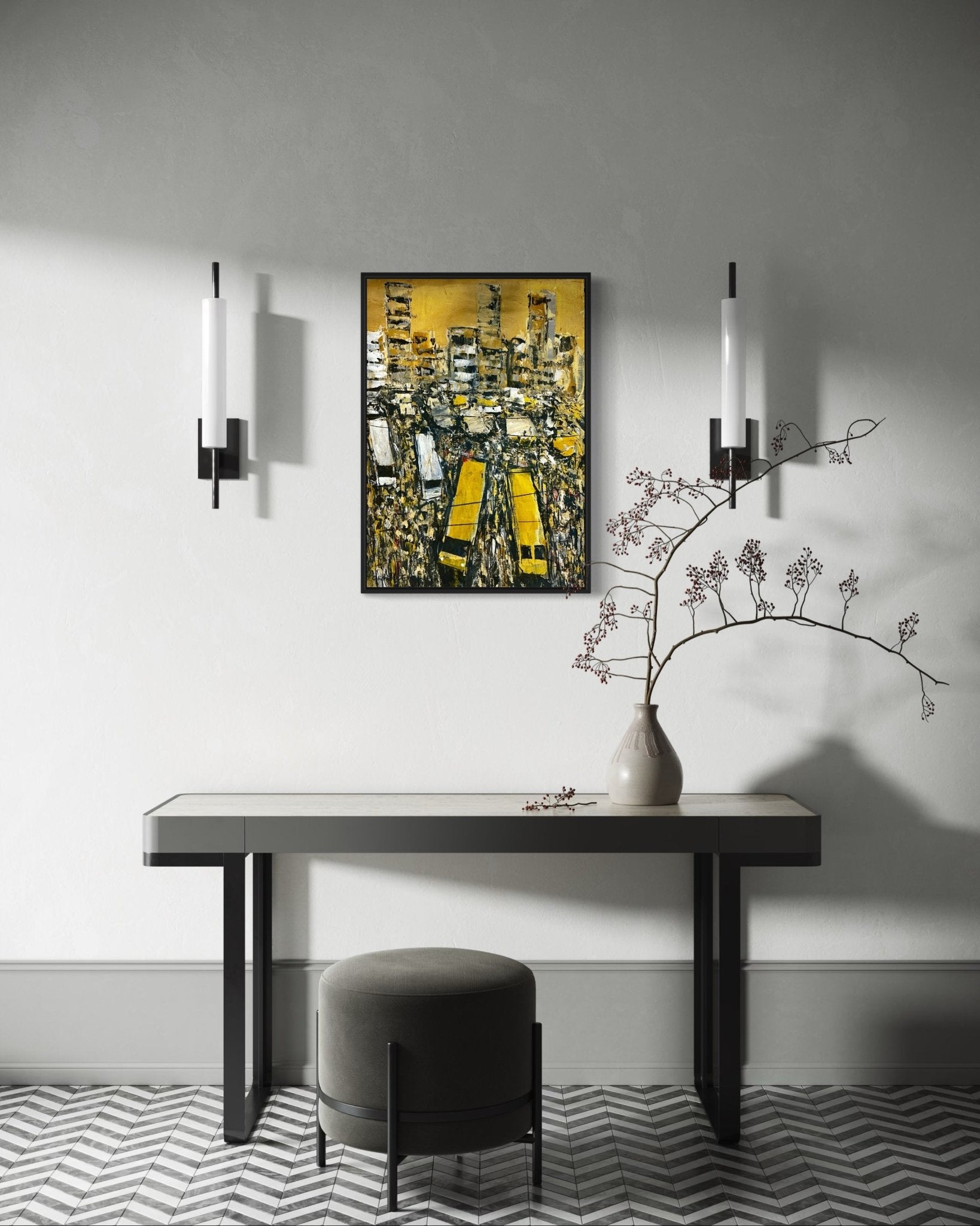 A modern entryway with a black-and-white chevron floor, a narrow console table, a round gray ottoman, wall sconces, a vase with branches, and "Danfo Life Lagos City" by Akhile Ehiforia—a painting depicting Lagos commuter life in yellow tones.